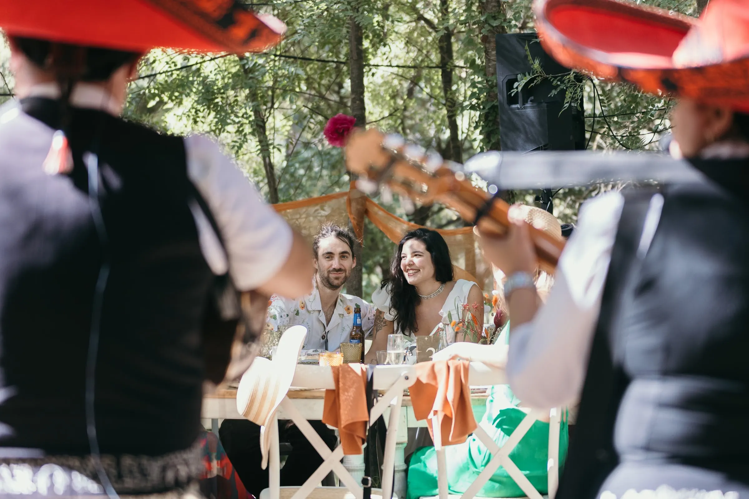 Musicians in red sombreros serenading the couple at their table