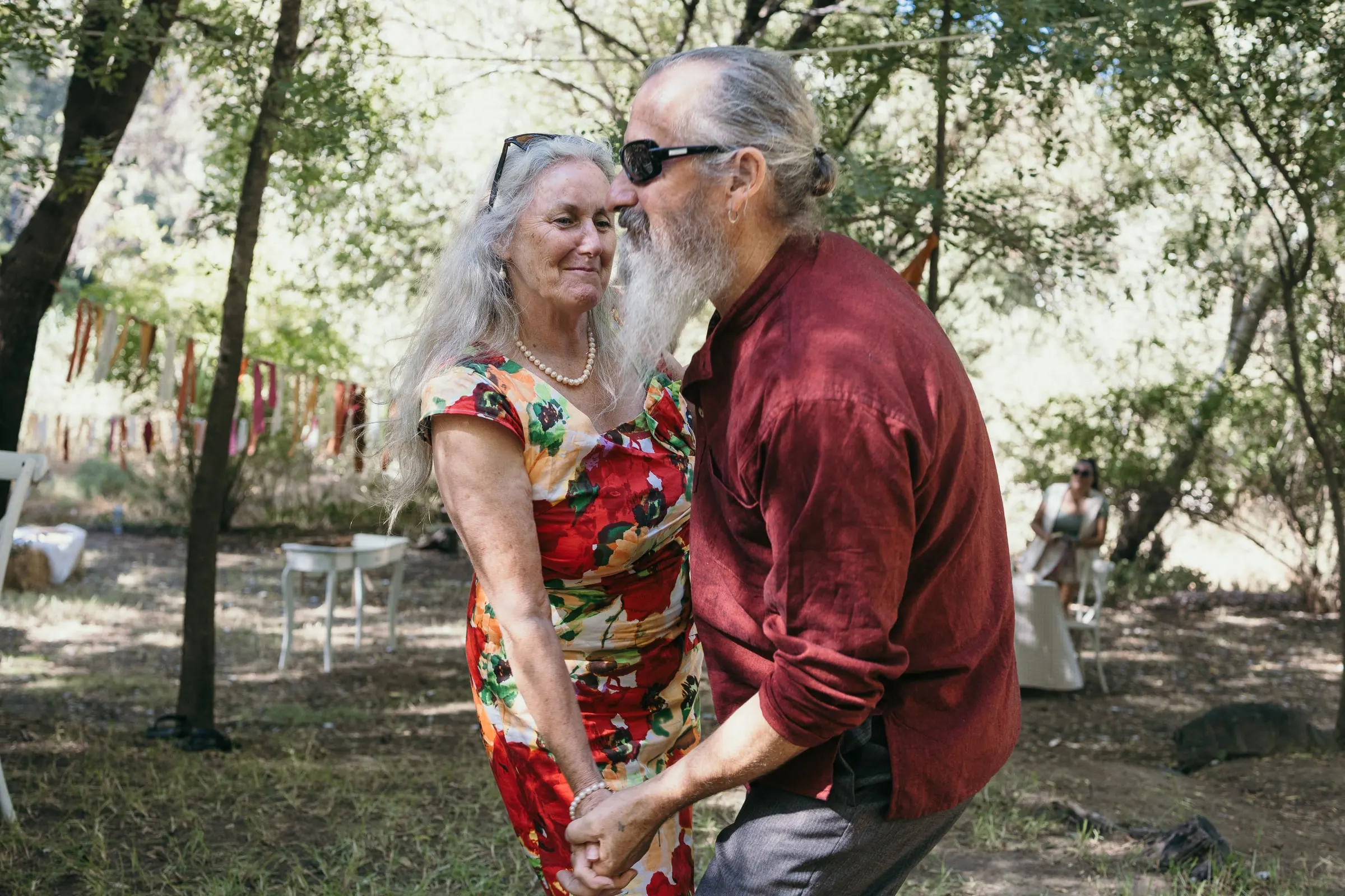Older couple dancing in the shade of the trees in the afternoon