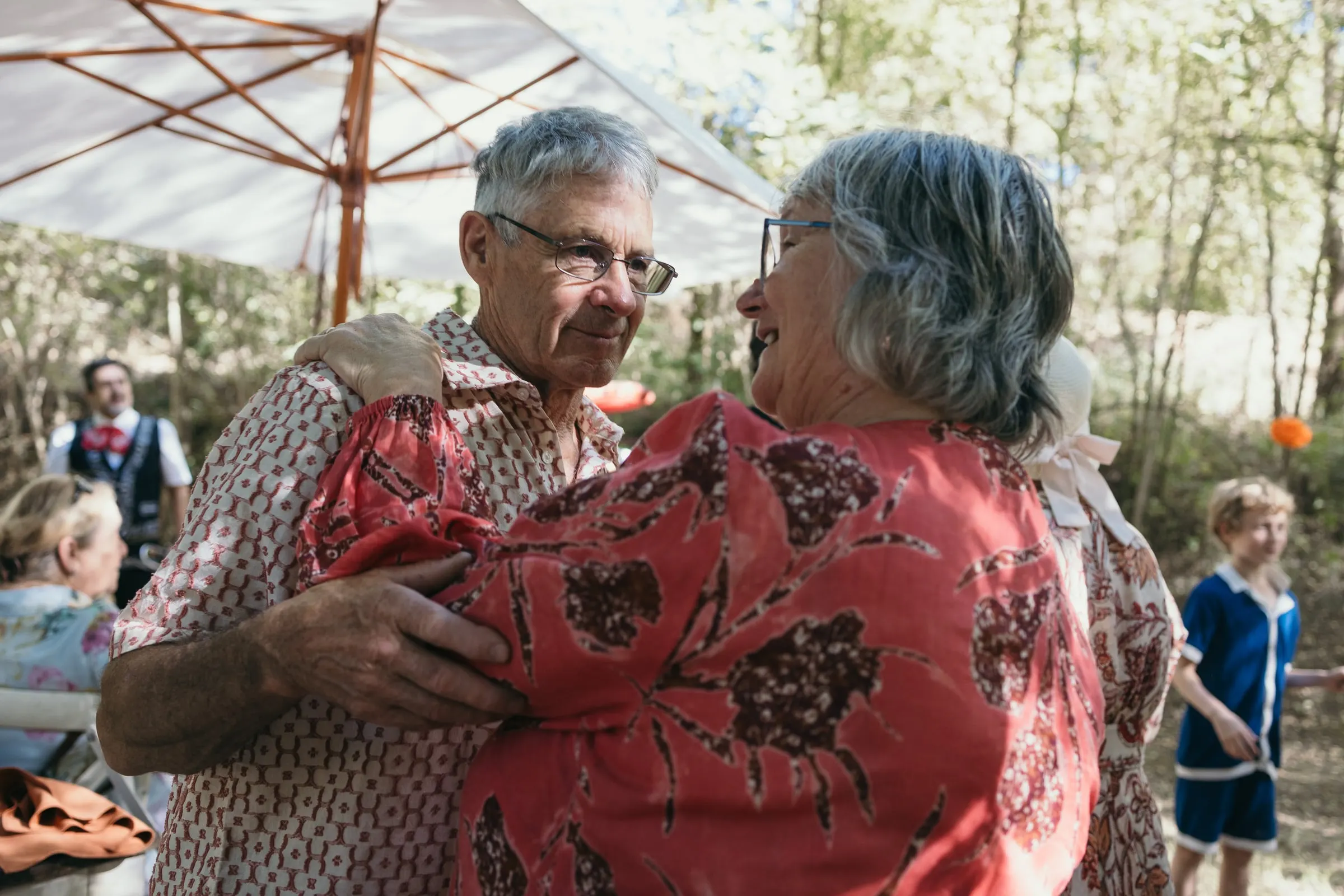 Groom's parents embracing under a parasol at the party