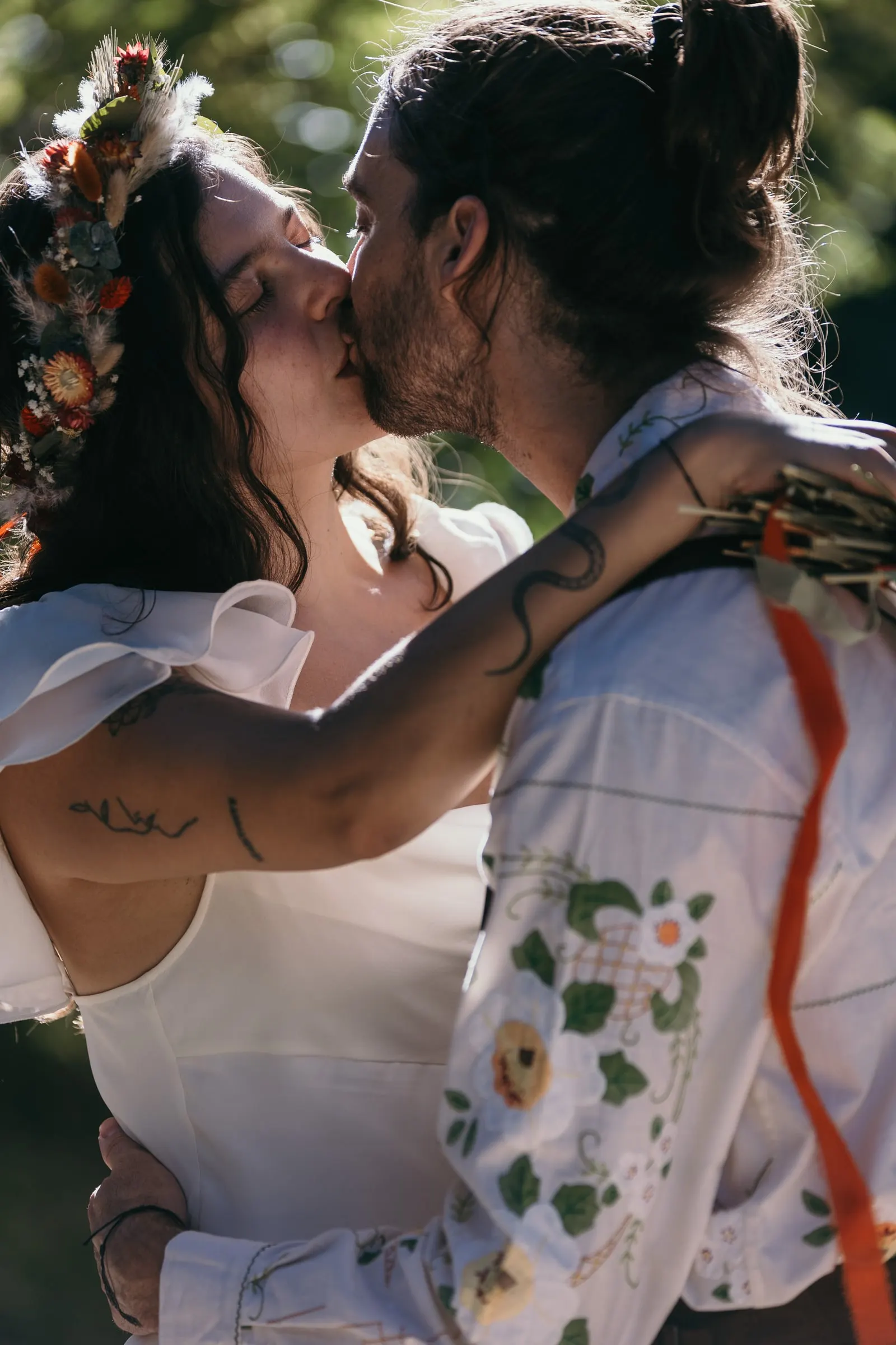 Close-up kiss, her flower crown and his embroidered shirt in the light