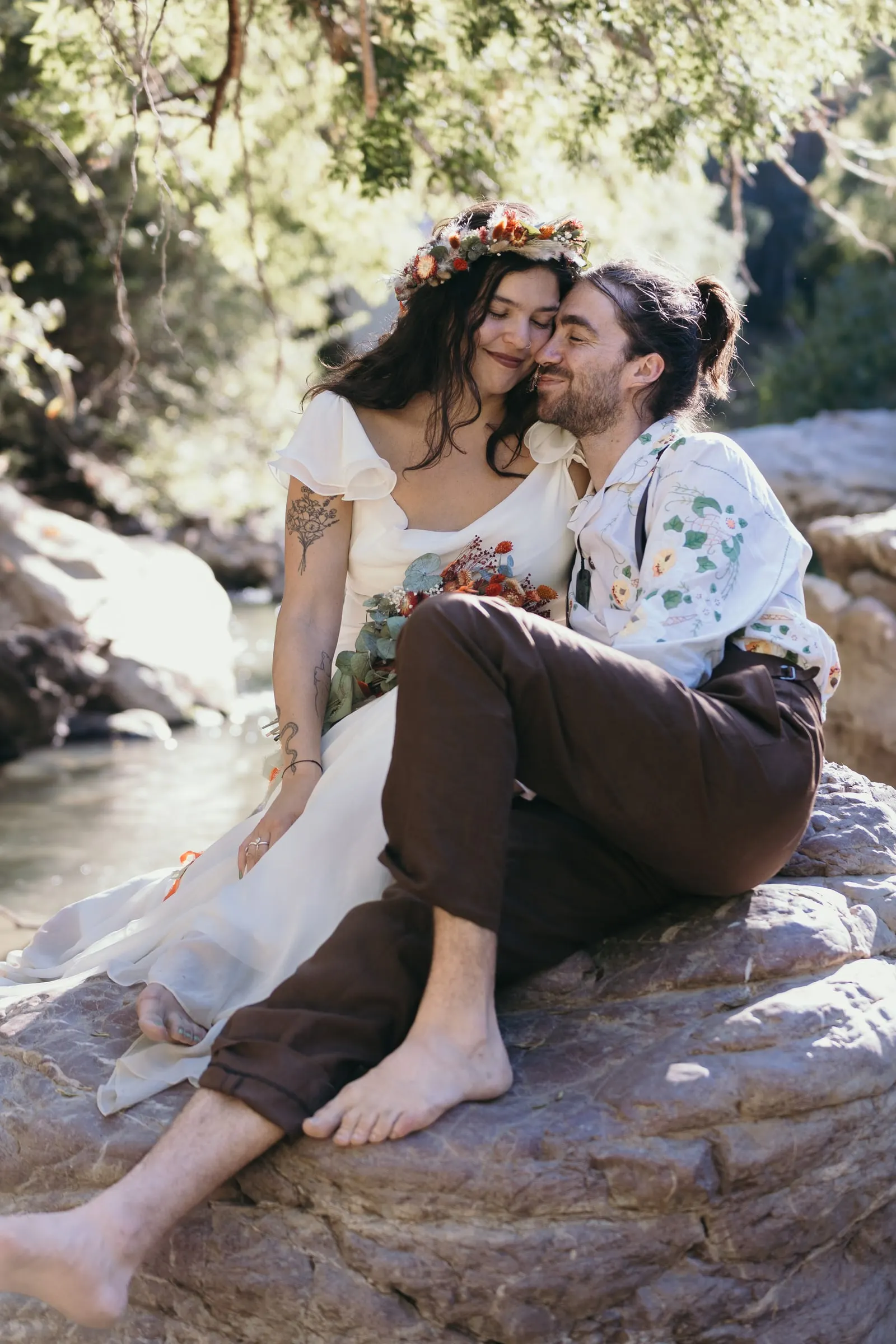 Barefoot couple sitting on a boulder beside the Guadiaro river at Molino La Flor