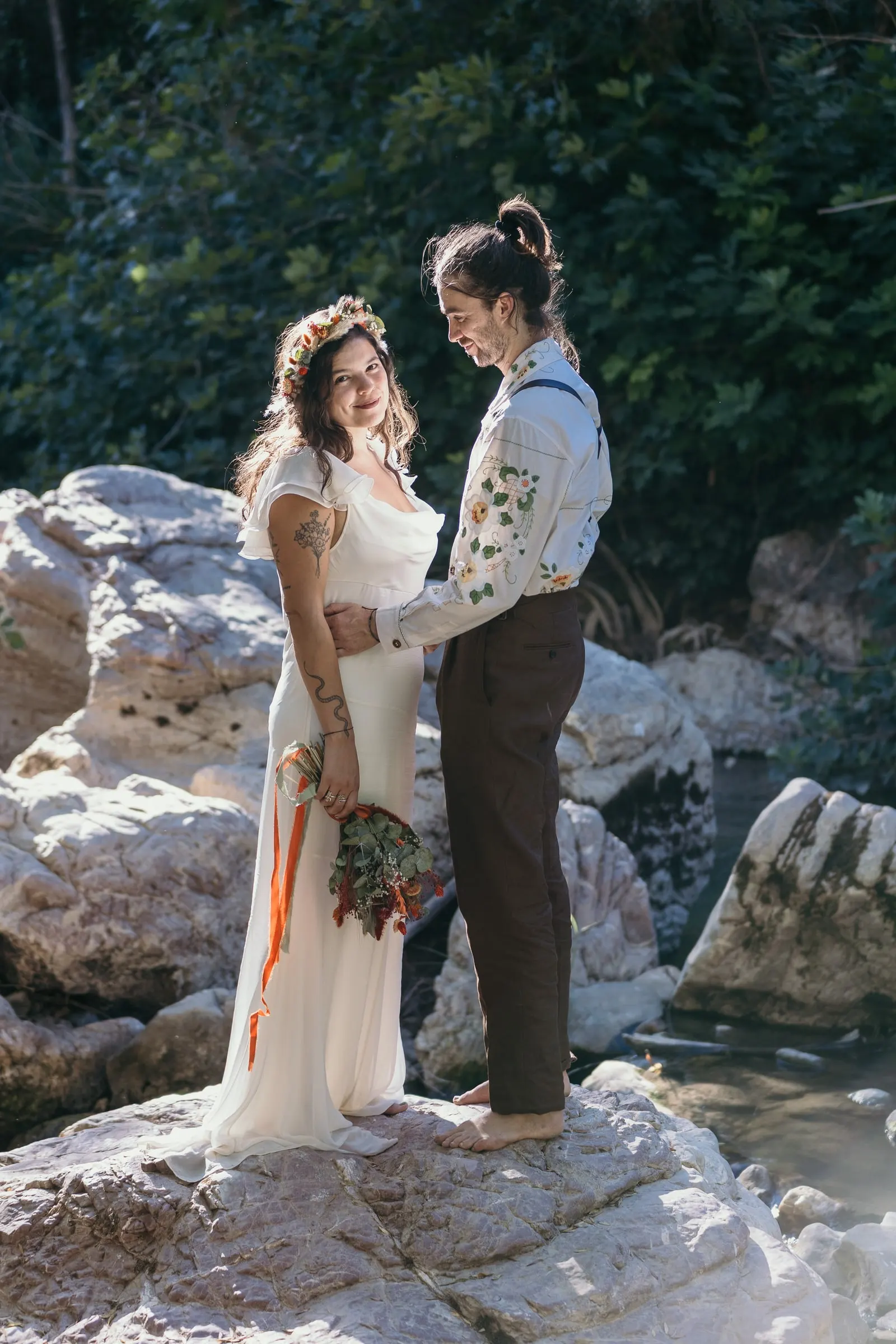 Bride and groom standing on white rocks in the river, Jimera de Líbar