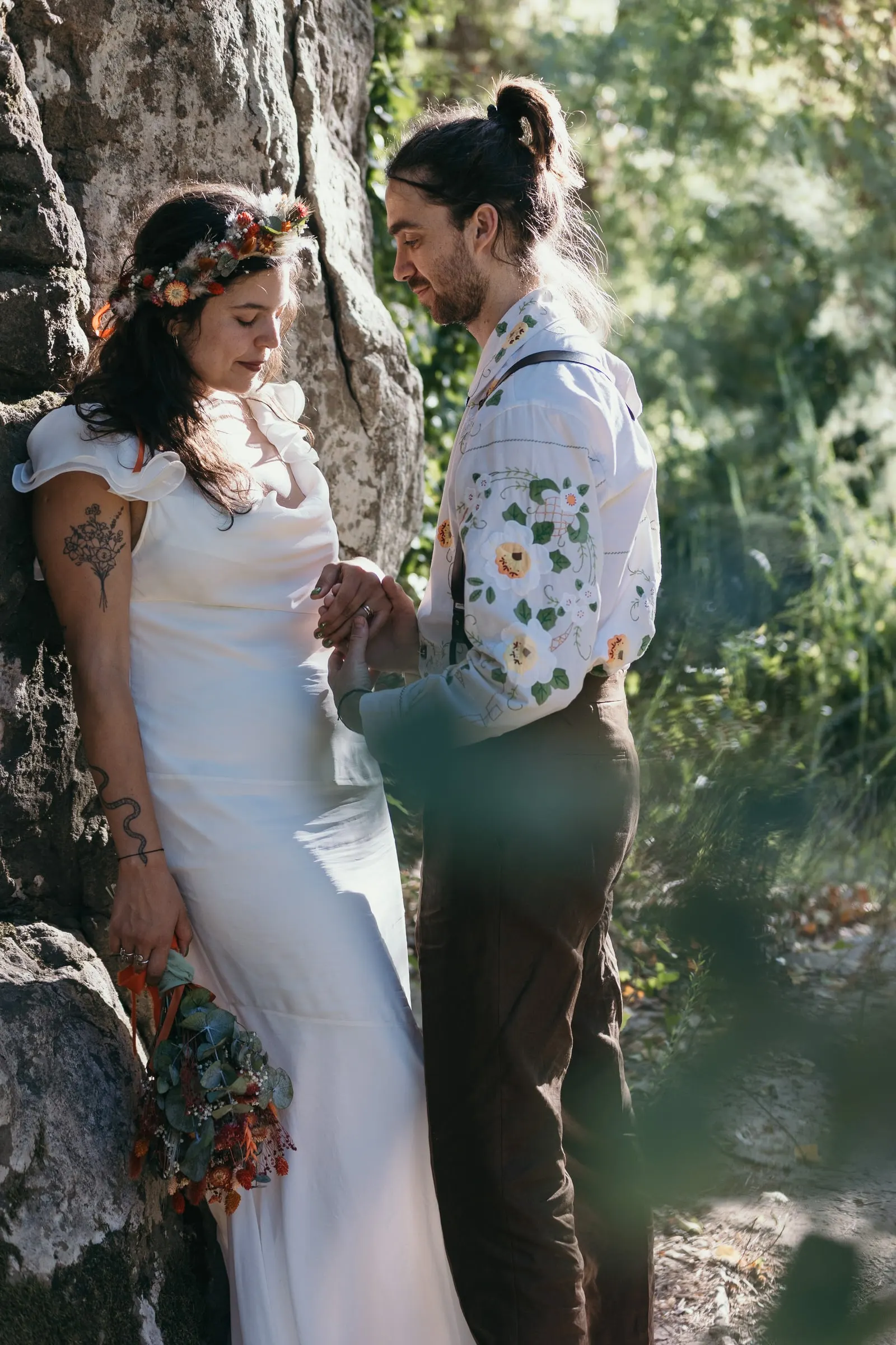 Bride and groom against a rock face in the shade by the river