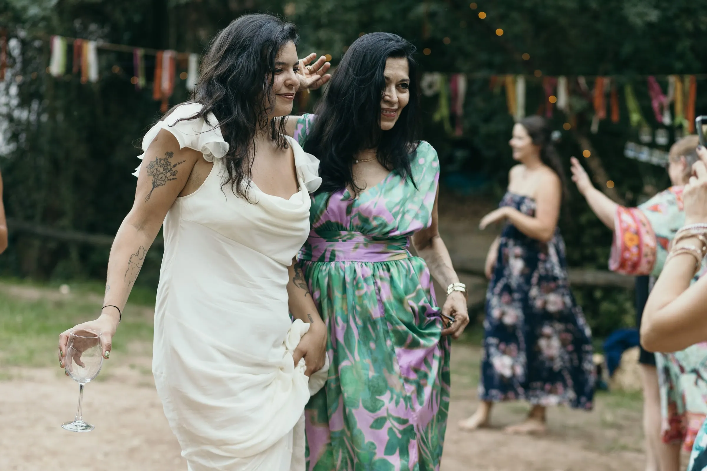 Bride dancing with a guest in a floral jumpsuit under the bunting