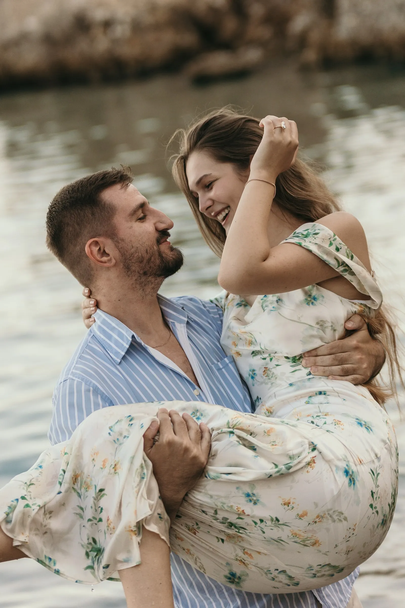 He carries her in his arms as she laughs with the sea behind, on the beach in Nerja