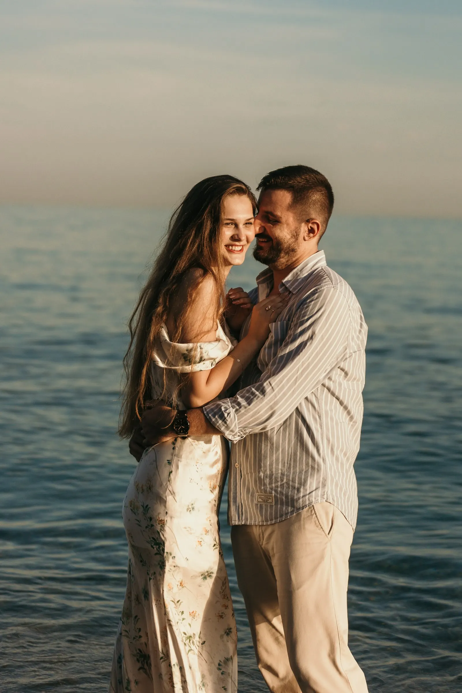 Couple cheek to cheek and smiling, standing in the calm sea, on the beach in Nerja