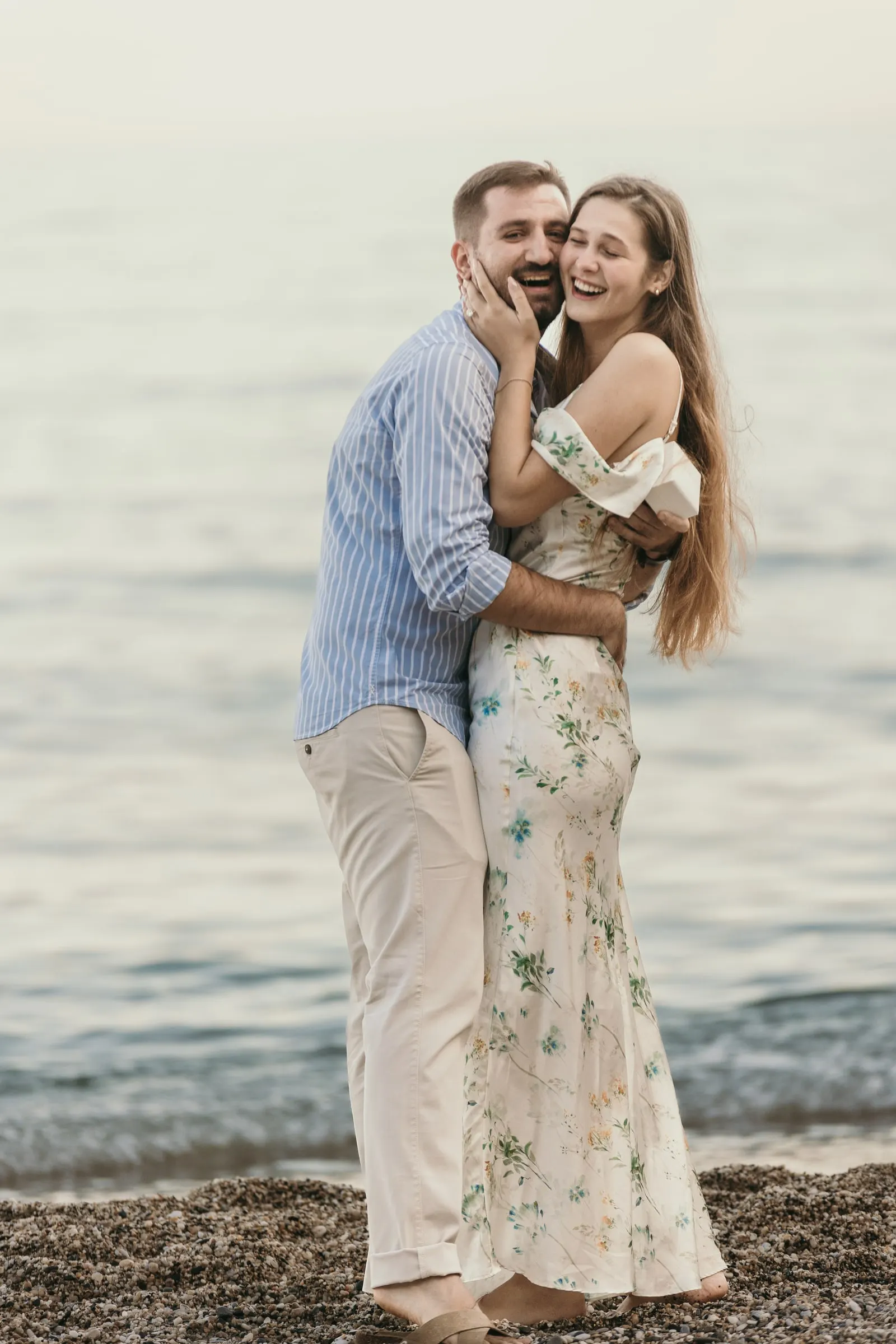 She holds his face and laughs as they hug on the shingle, on the beach in Nerja