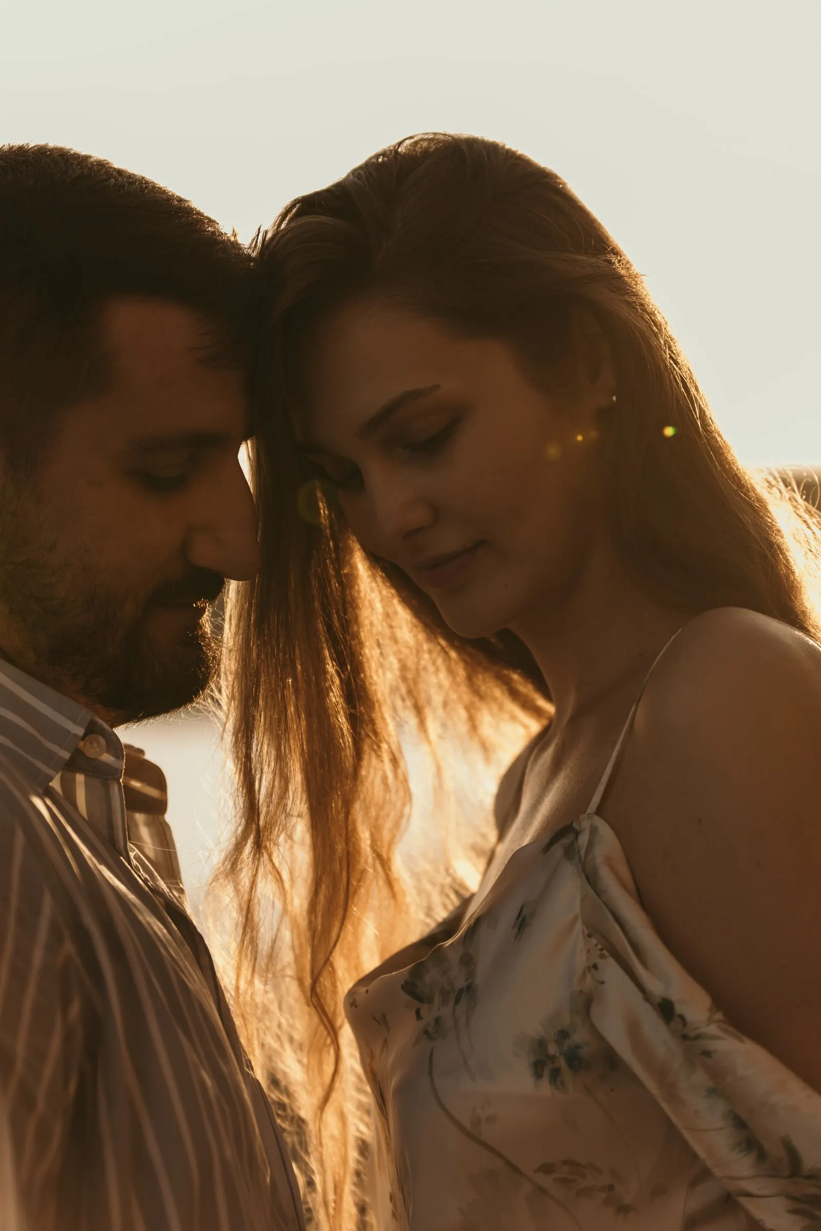 Couple forehead to forehead with the low sun shining through her hair, beach in Nerja