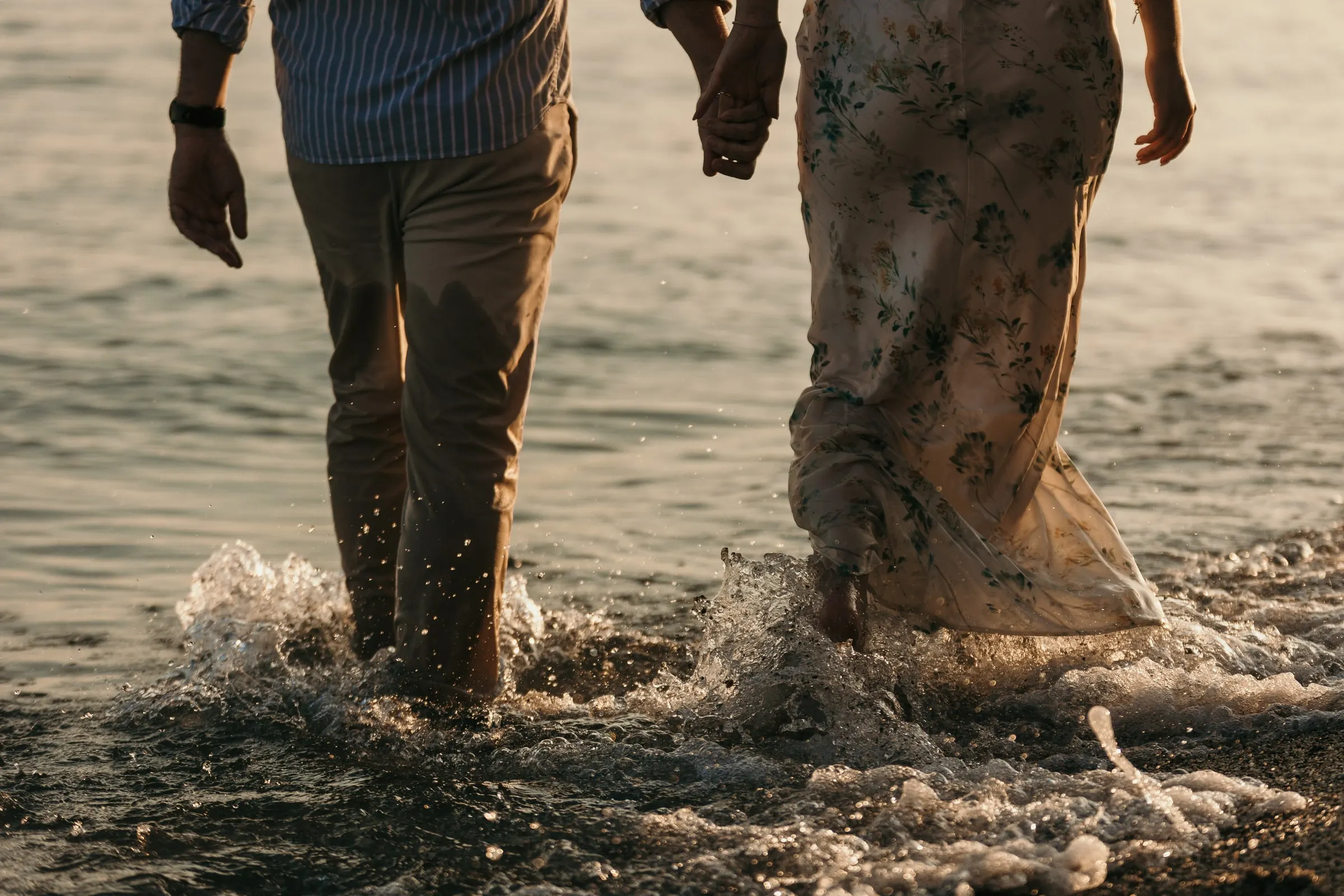 Close-up of their legs splashing through the waves as they walk, on the beach in Nerja
