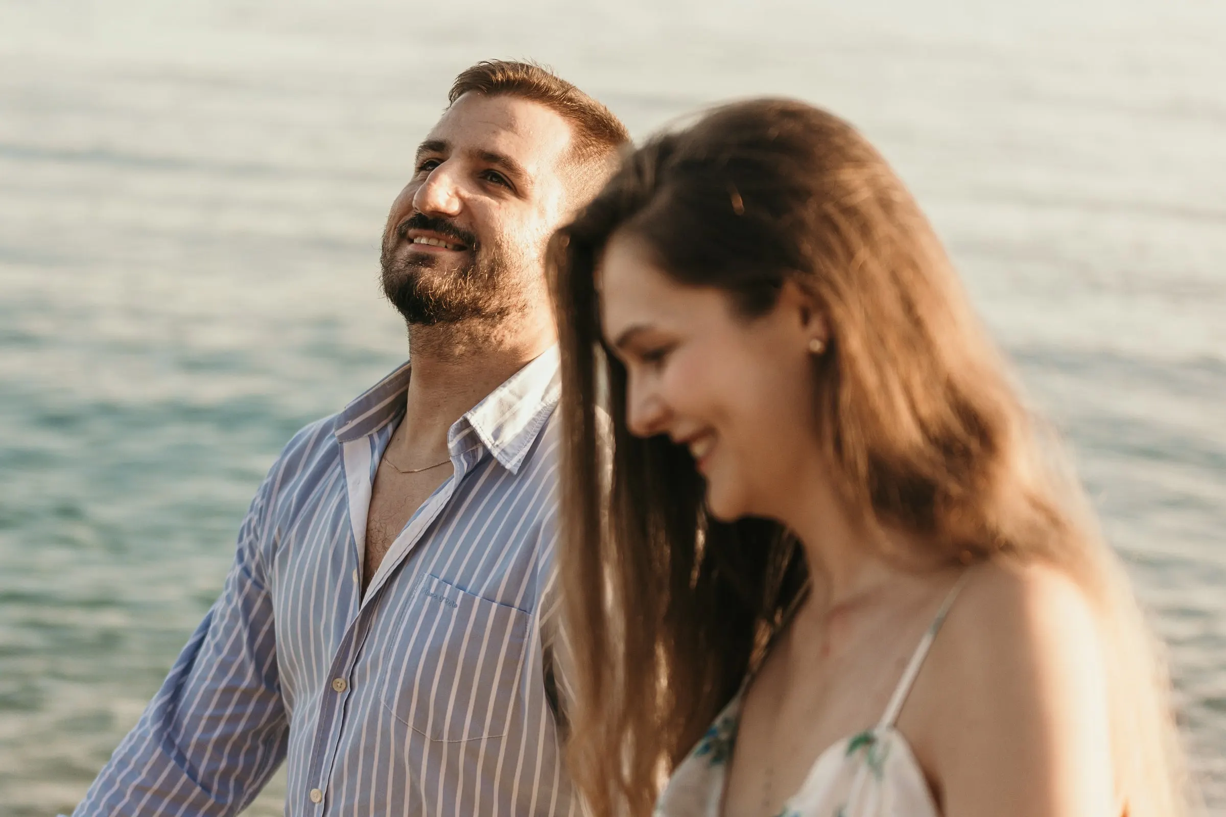 He laughs with his eyes closed as she smiles beside him by the sea, on the beach in Nerja