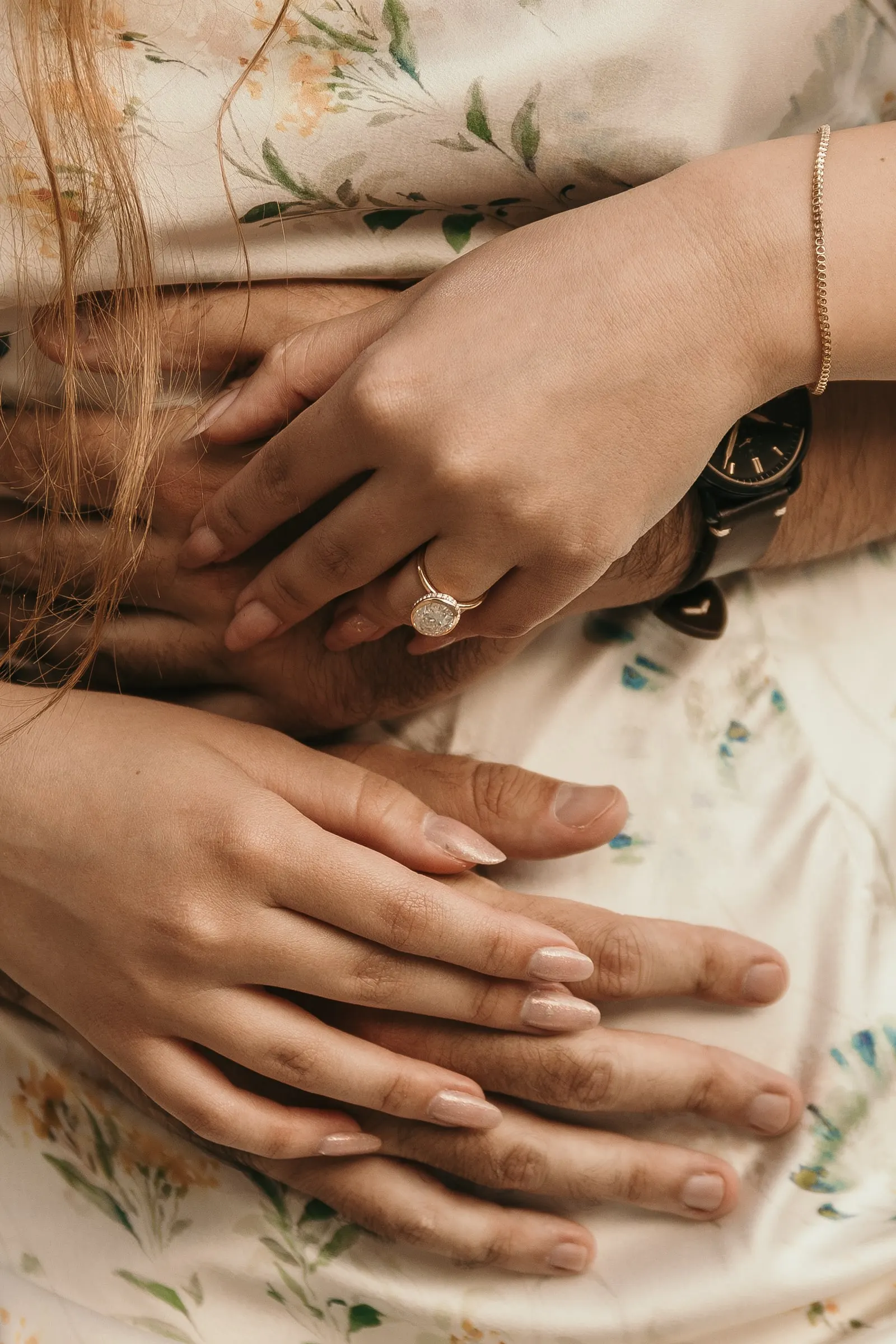 Close-up of her hands with the new engagement ring over his, on the beach in Nerja