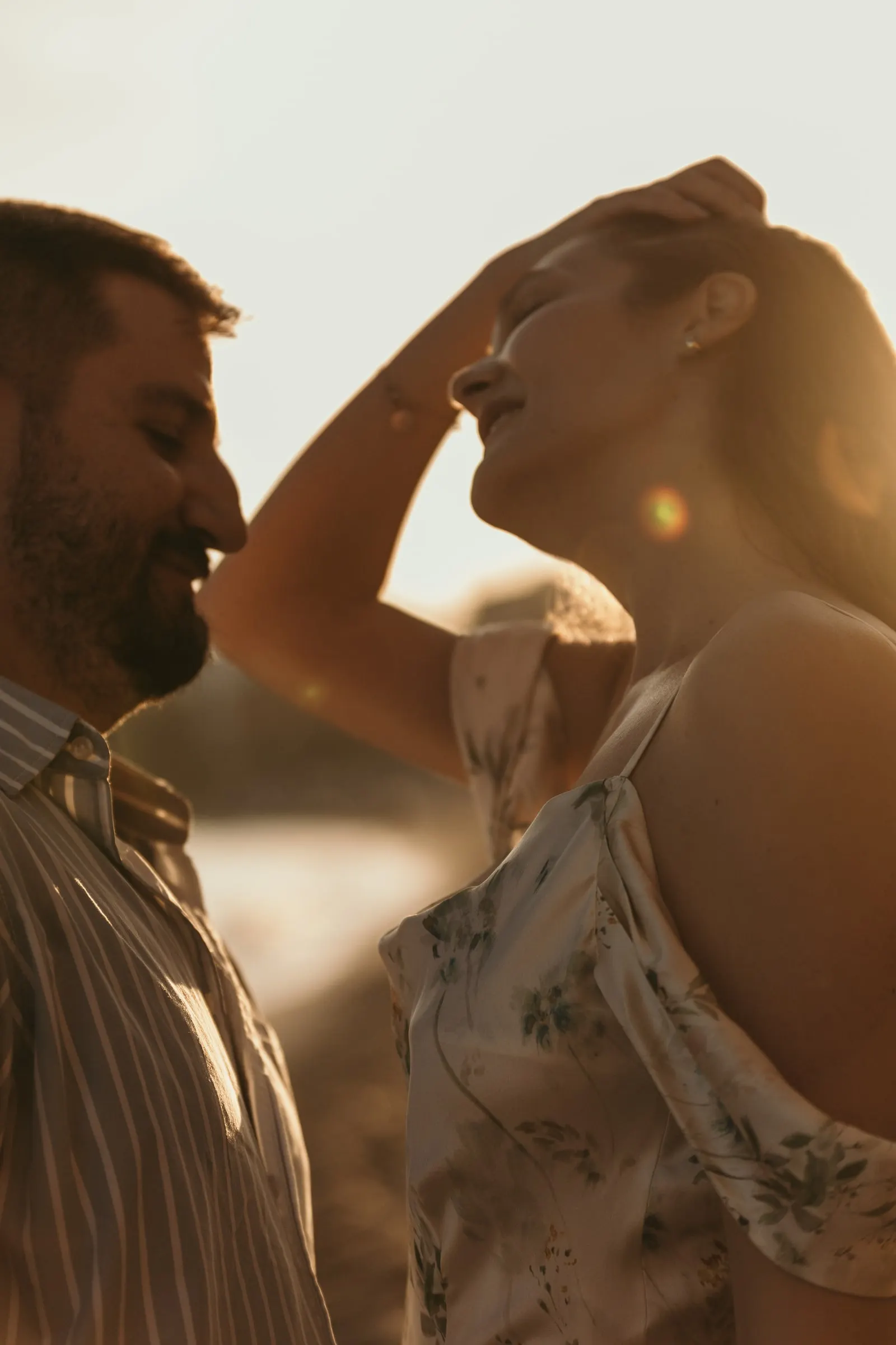 She lifts her hair and laughs as he smiles at her in the sunset light, on the beach in Nerja