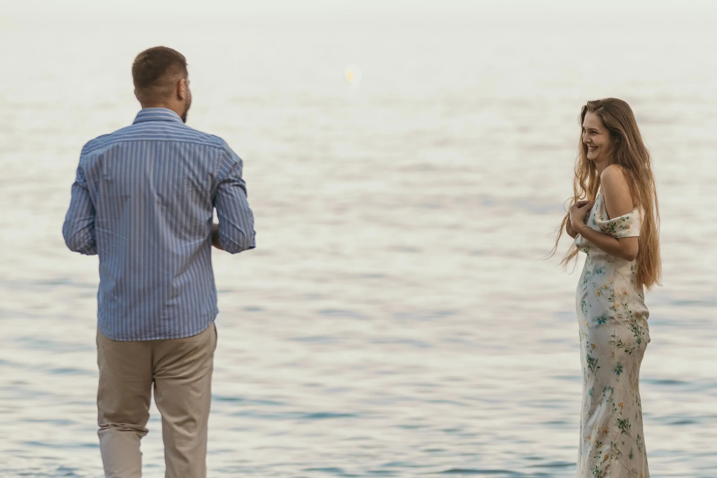He walks towards her as she smiles at the water's edge, on the beach in Nerja
