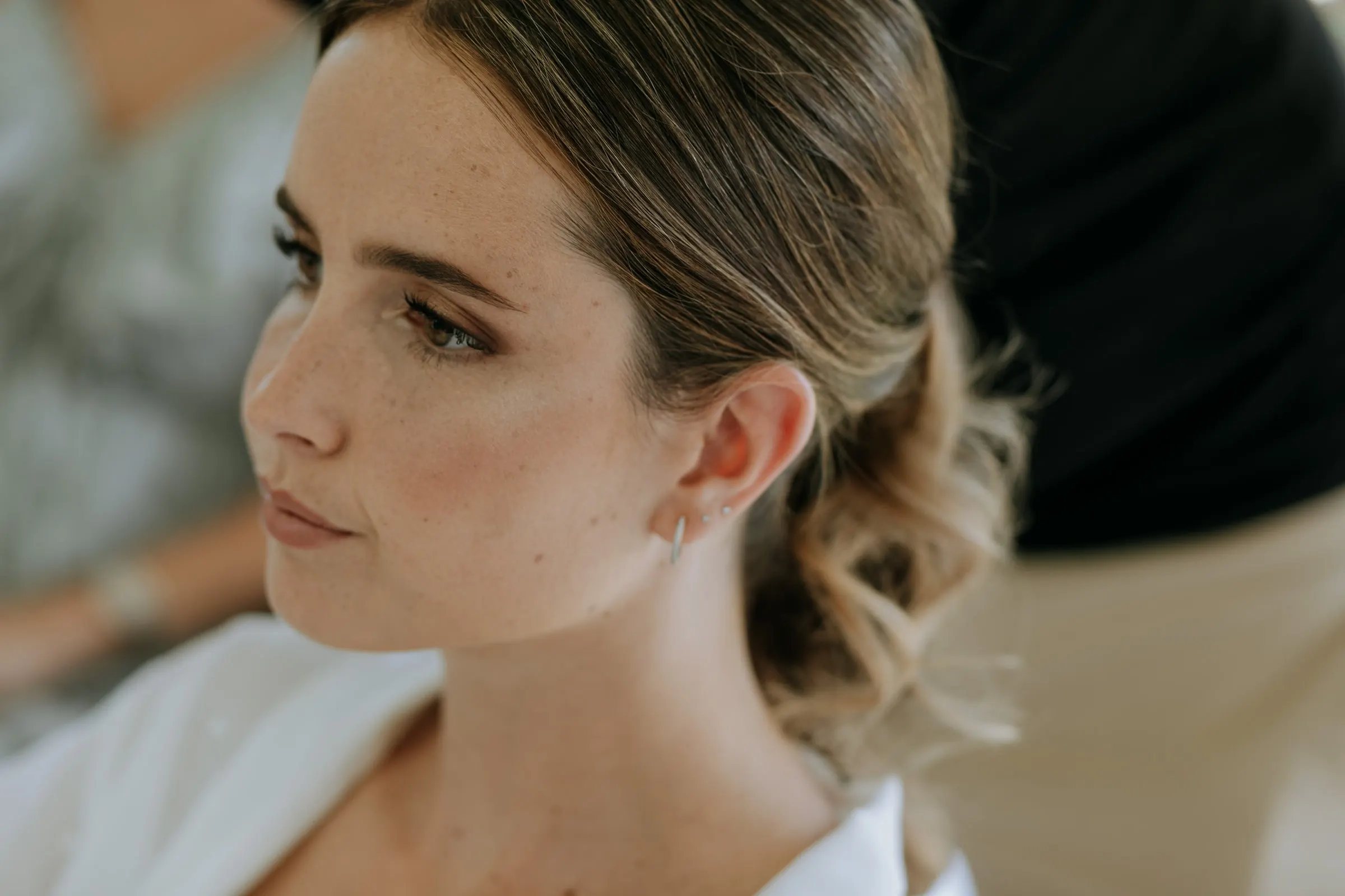 Close profile of the bride with her hair half up and pearl earrings