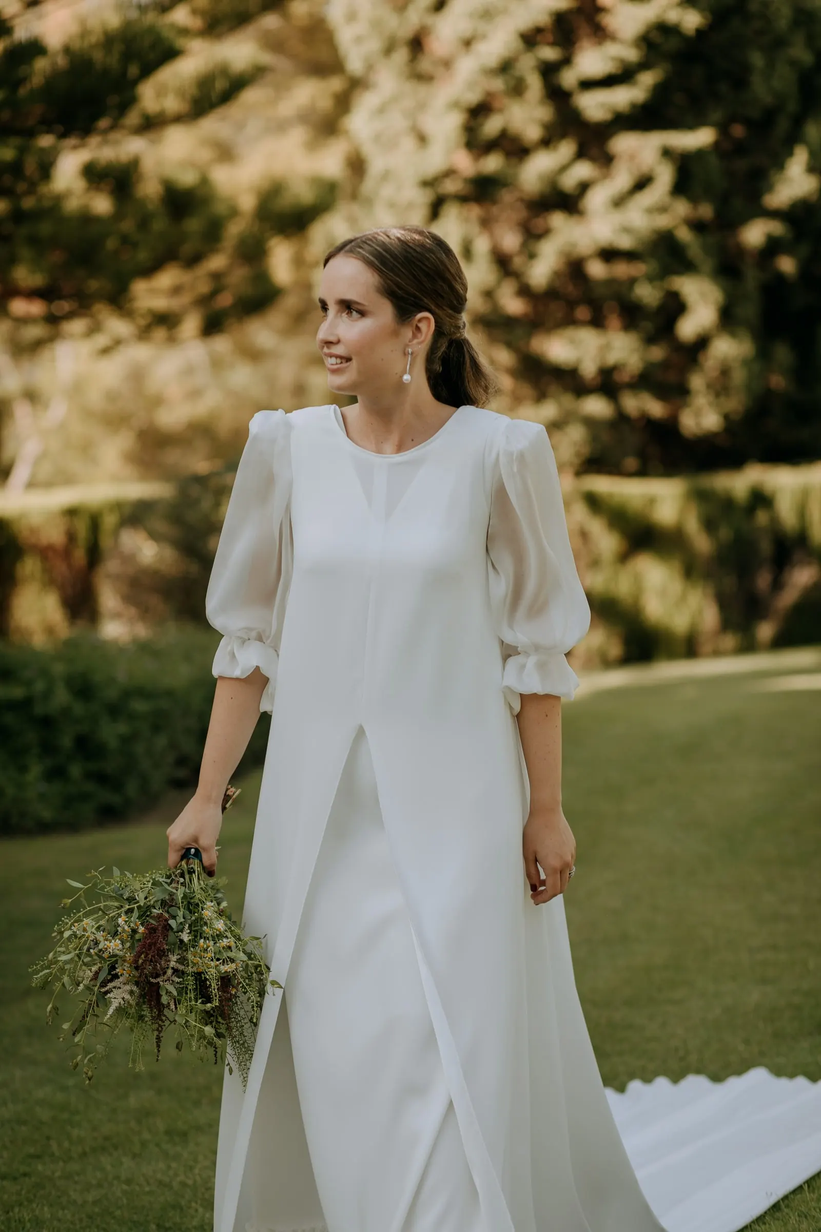 Bride glancing over her shoulder on the lawn, bouquet in hand and train behind her, Sotogrande