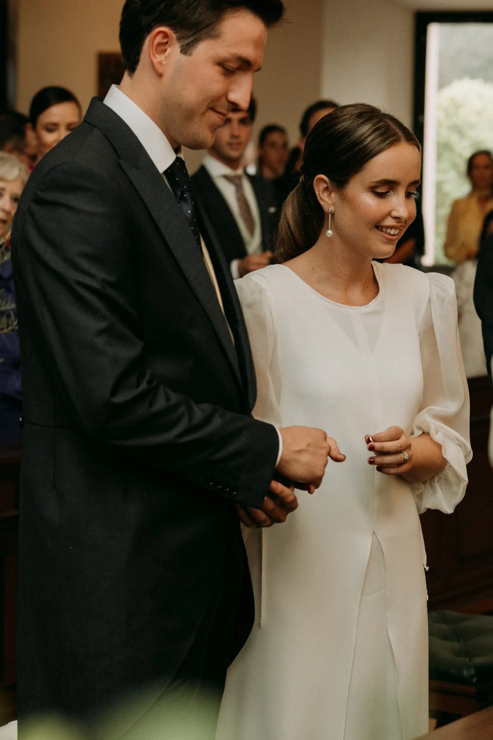 Bride smiling down at her new wedding ring beside the groom