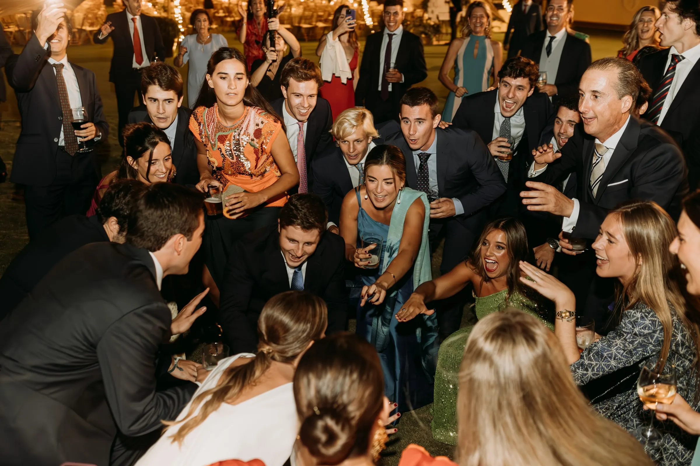 Guests crouching and cheering in a circle on the lawn during the party in Sotogrande