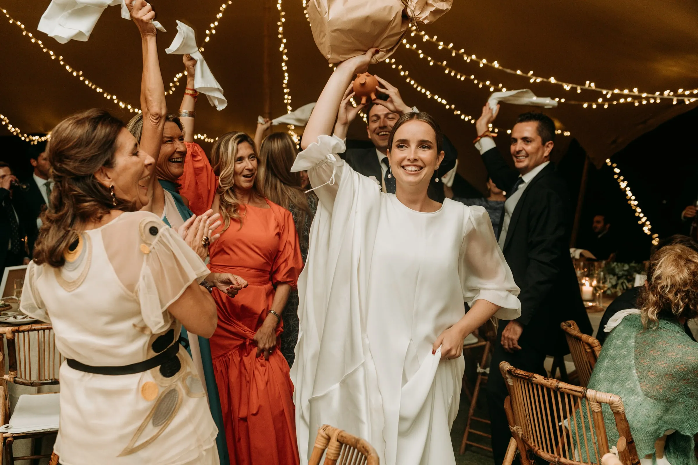 Bride and guests waving napkins in the air between the tables under the tent