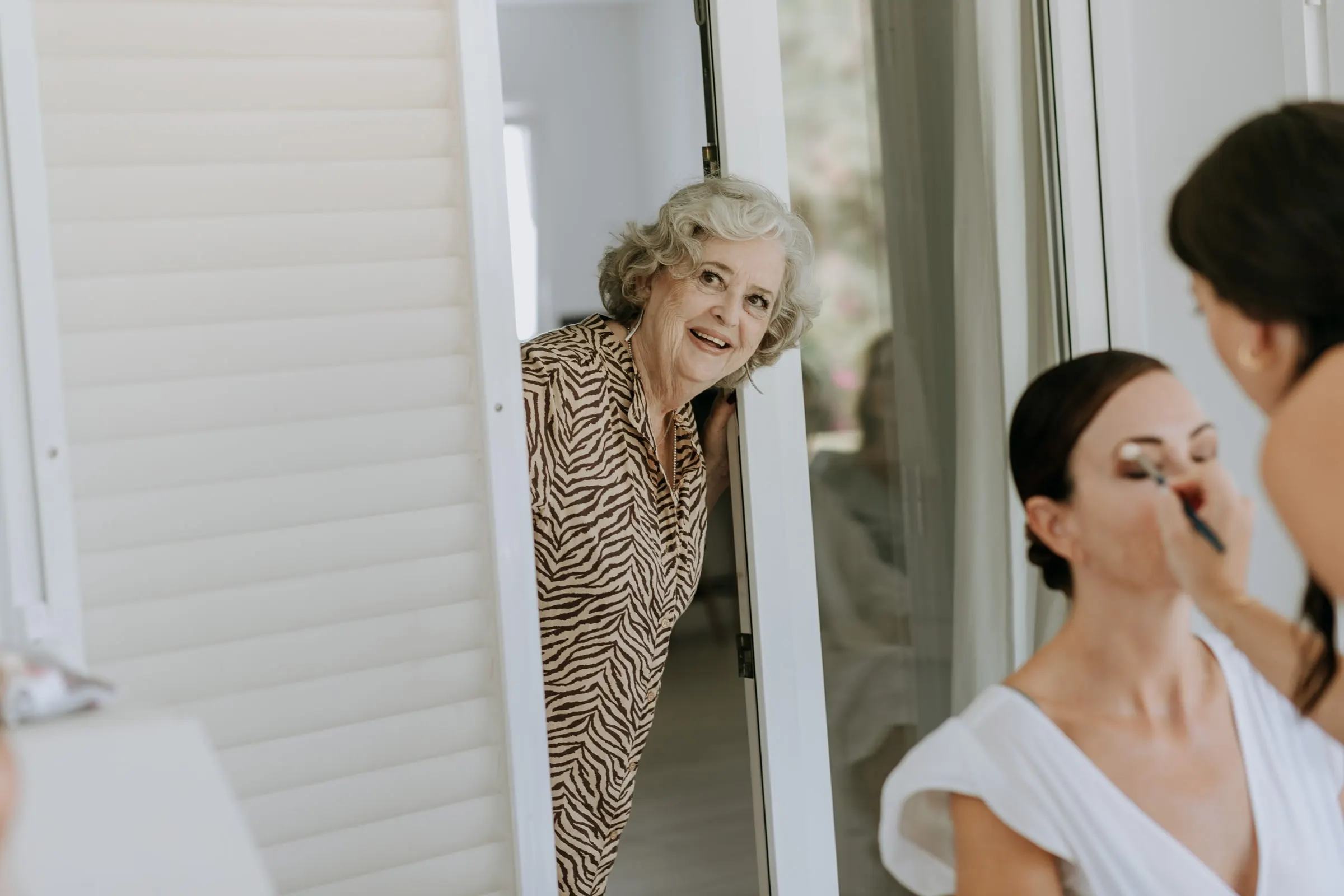 Grandmother peeking round the door while a guest has her make-up done