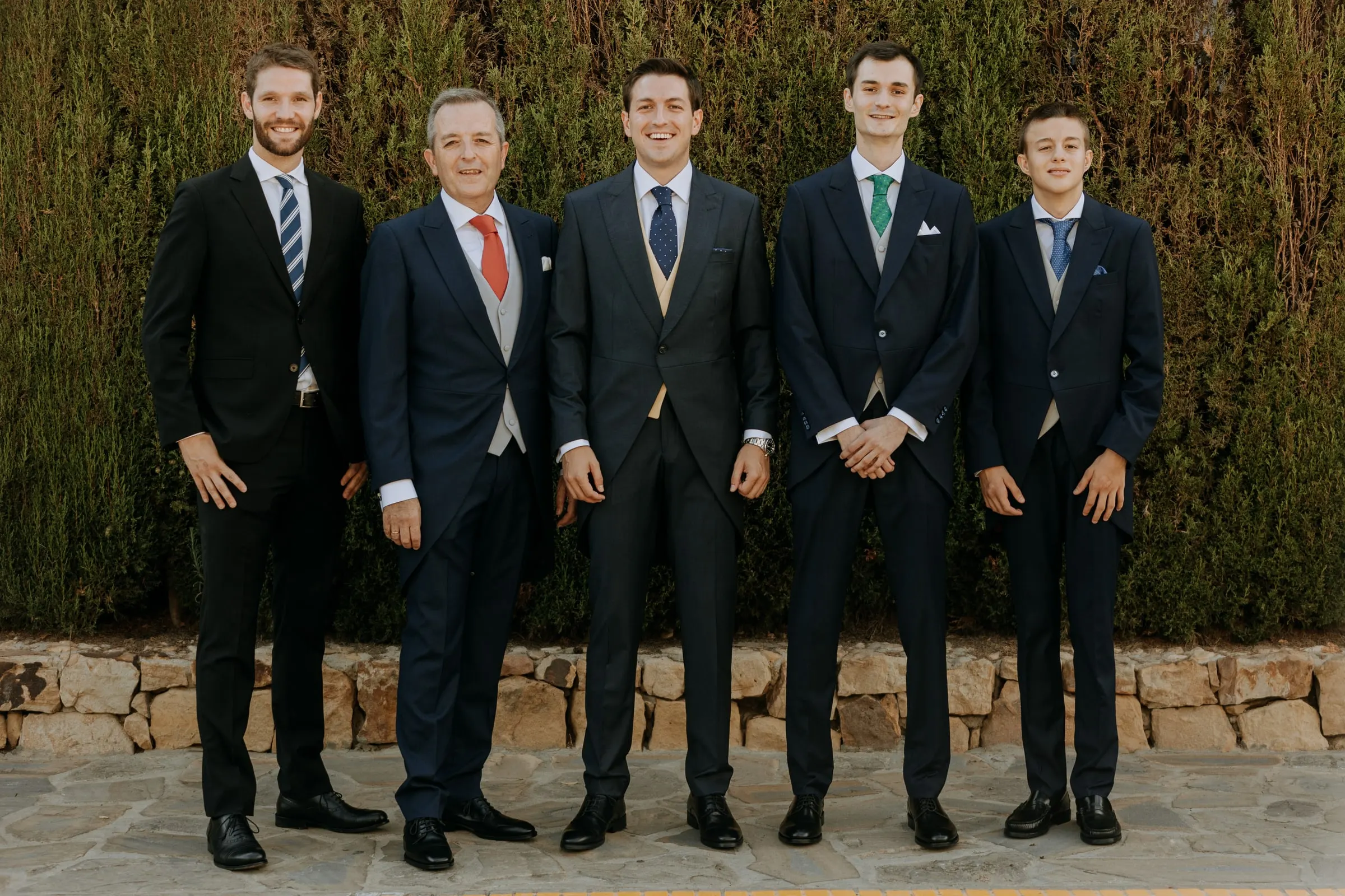Groom and his men in morning suits against a garden hedge in Sotogrande