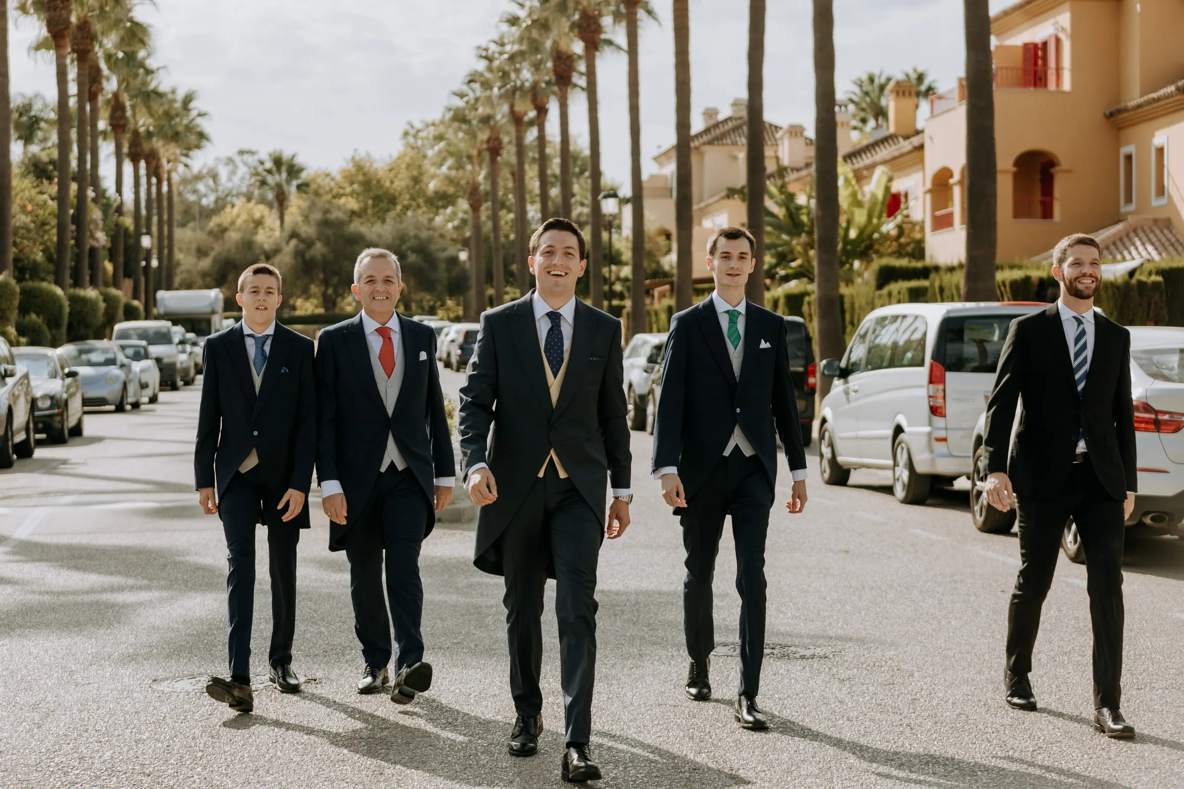 Groom walking with his men down a palm-lined avenue in Sotogrande