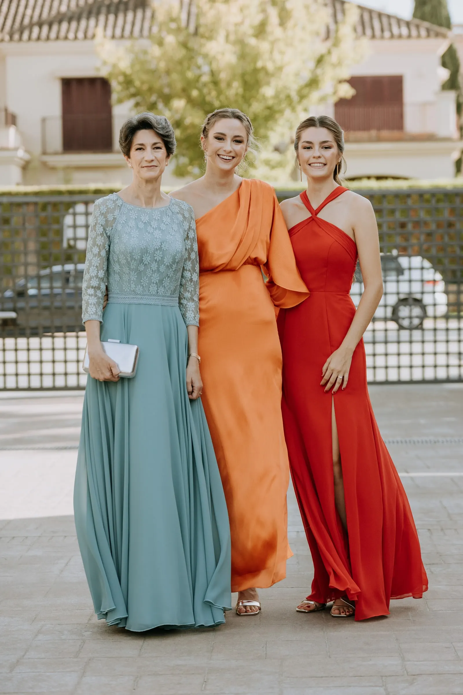 Three guests in blue, orange and red long dresses outside the house in Sotogrande