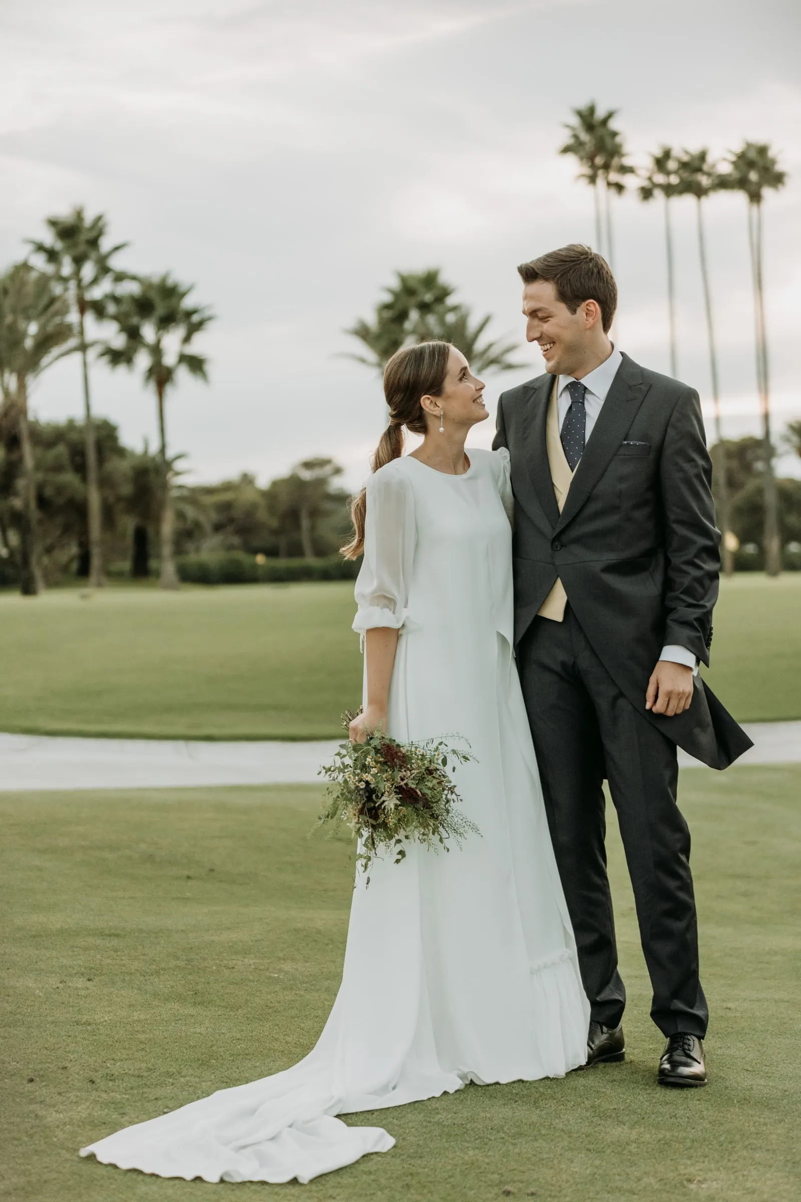 Bride and groom on a golf course lined with palm trees in Sotogrande