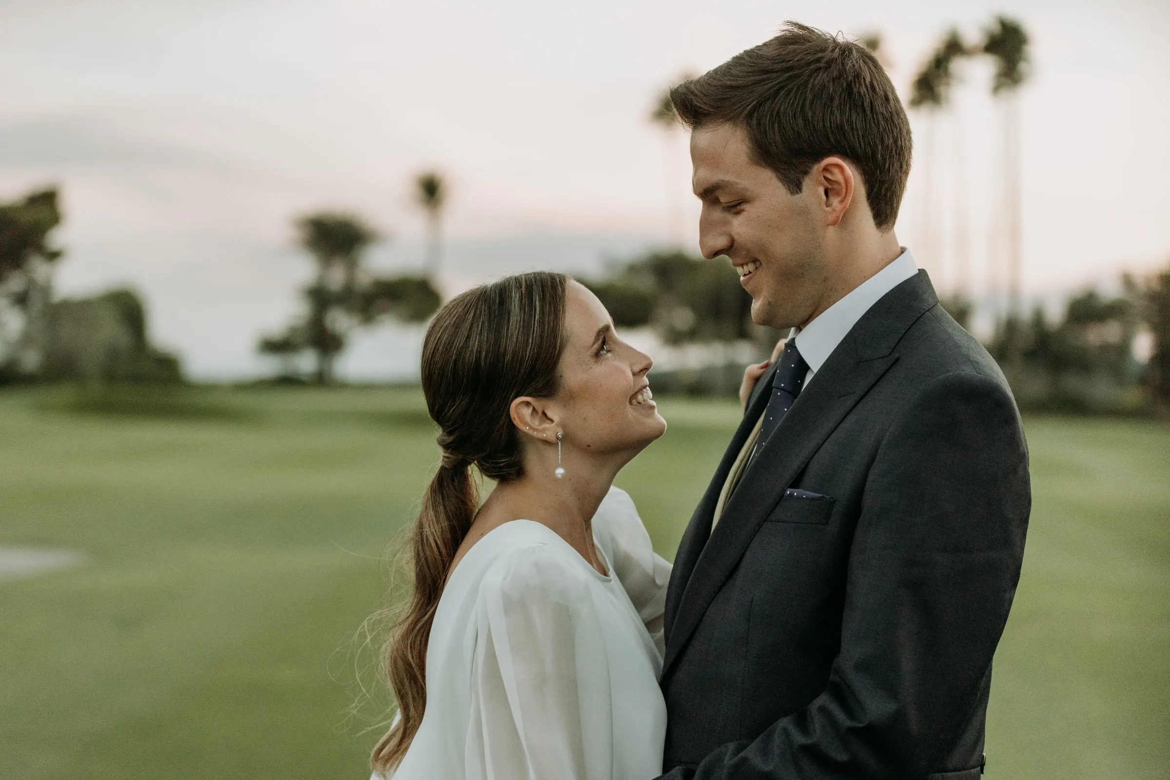 Bride and groom looking at each other on the golf course at sunset in Sotogrande
