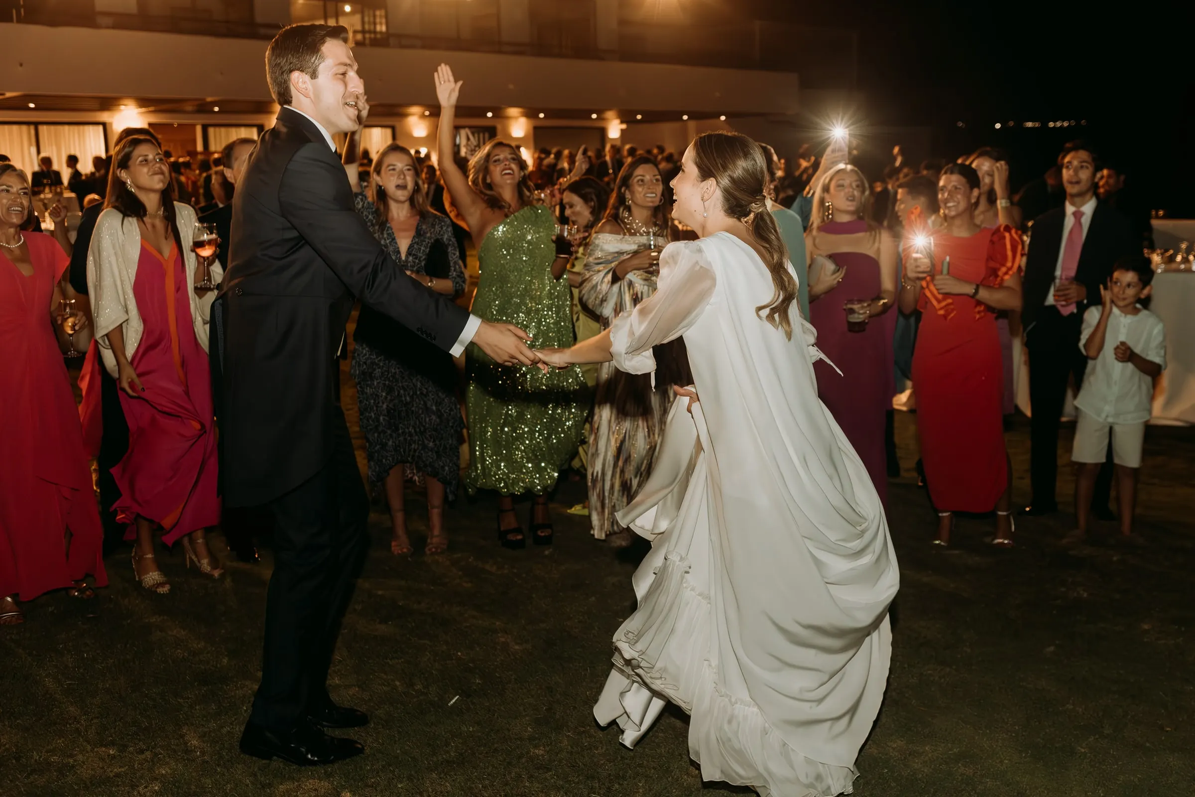 Bride and groom dancing among guests at the start of the party