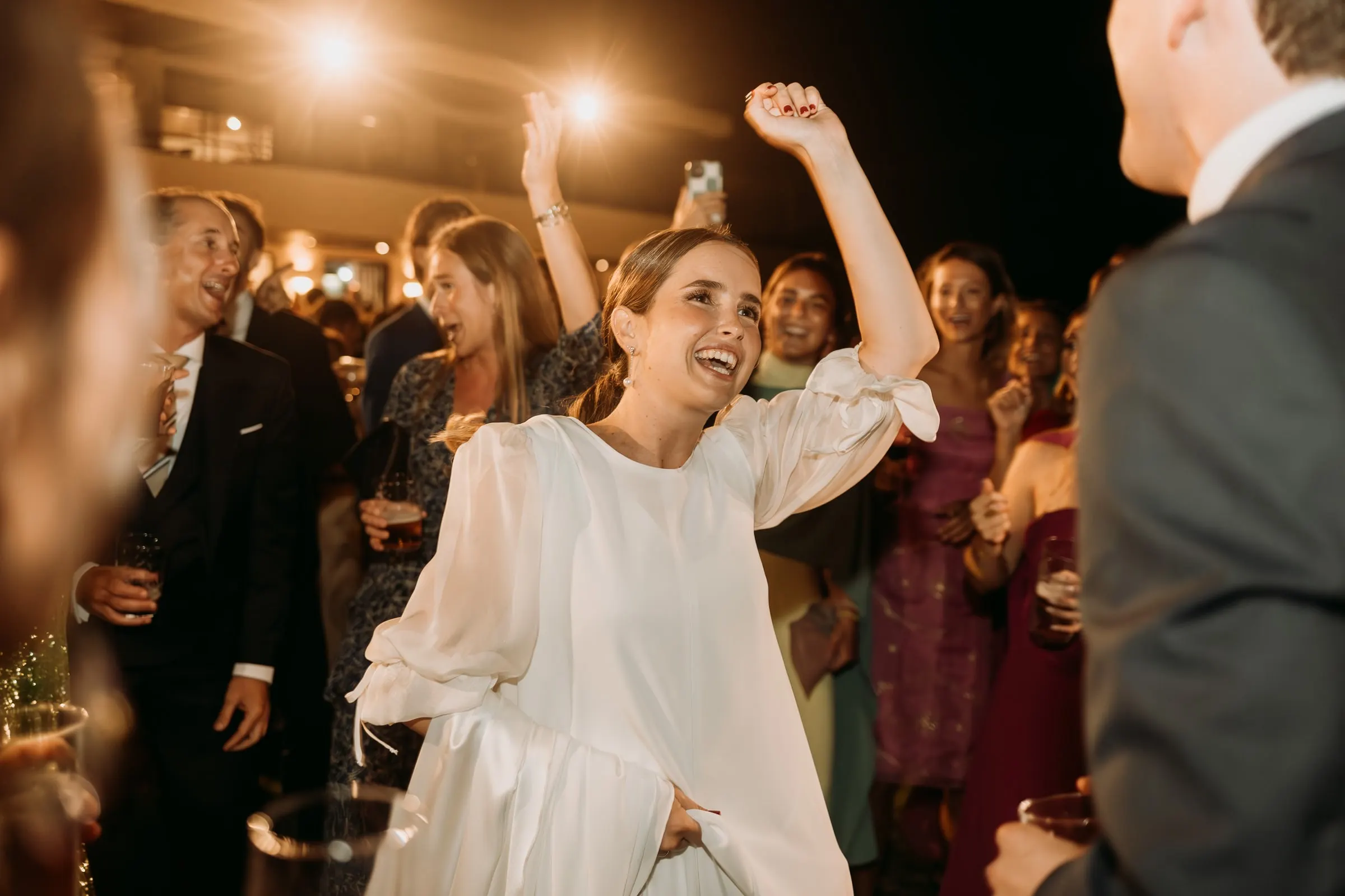 Bride throwing her arm in the air among the guests