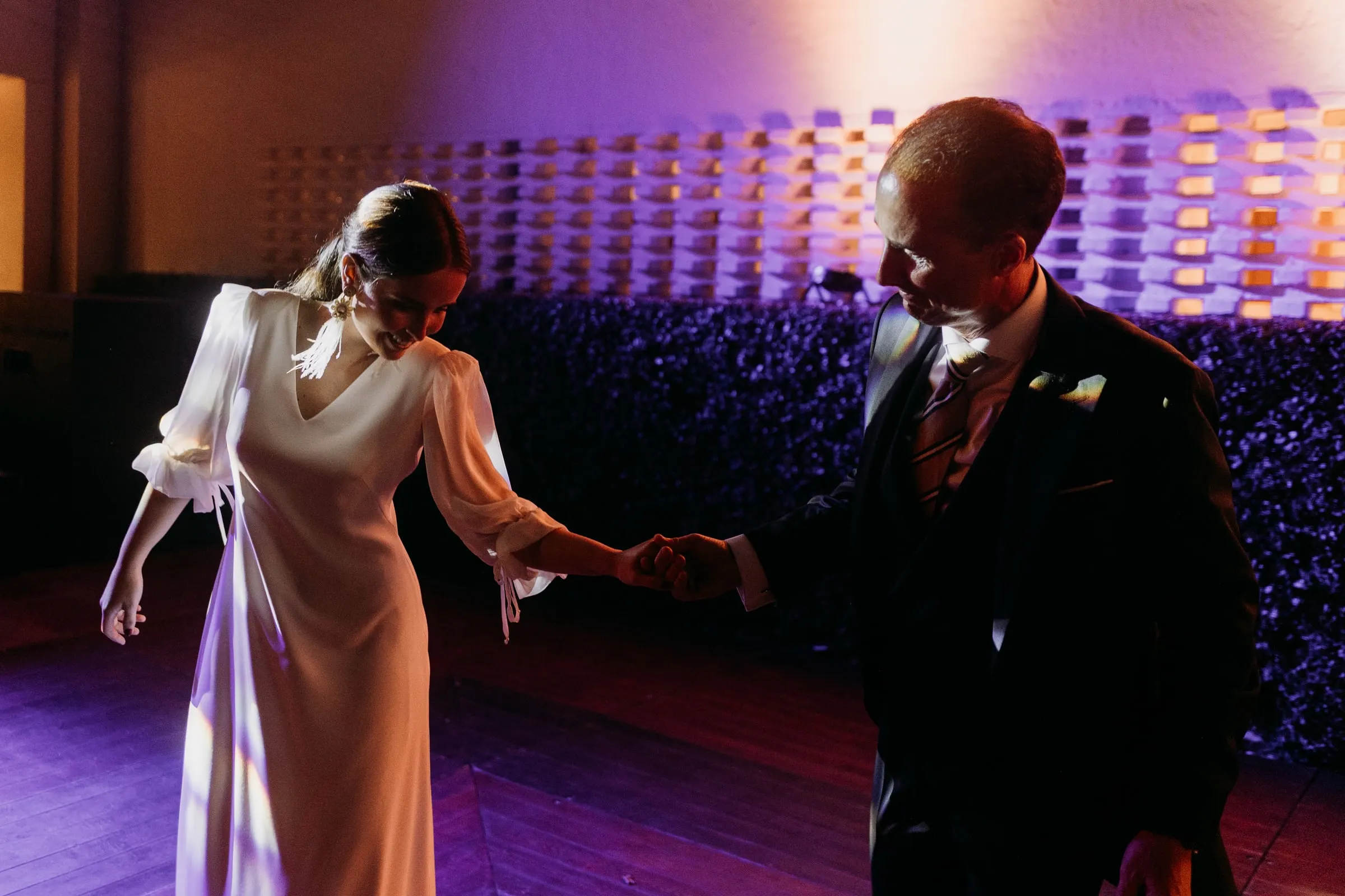 Bride dancing with a family member under purple light in Sotogrande