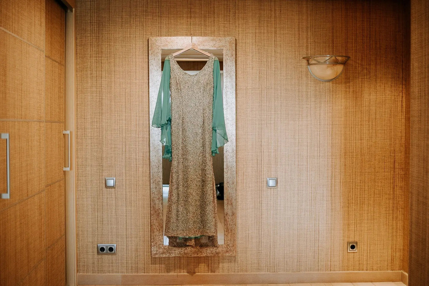 Silver dress with a turquoise cape hanging on a wardrobe mirror