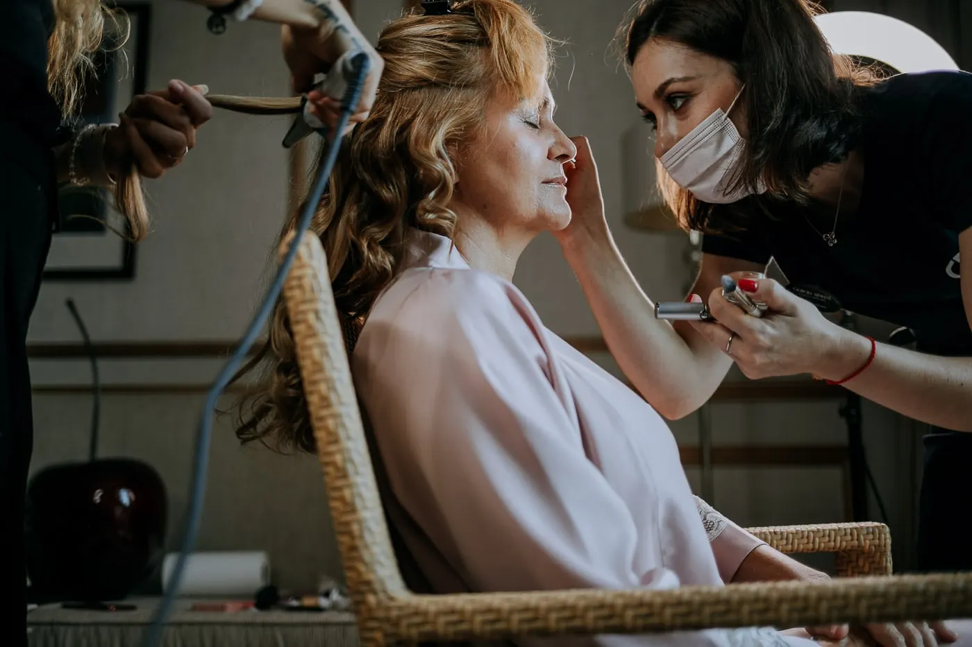 Bride in a pink robe having her make-up done