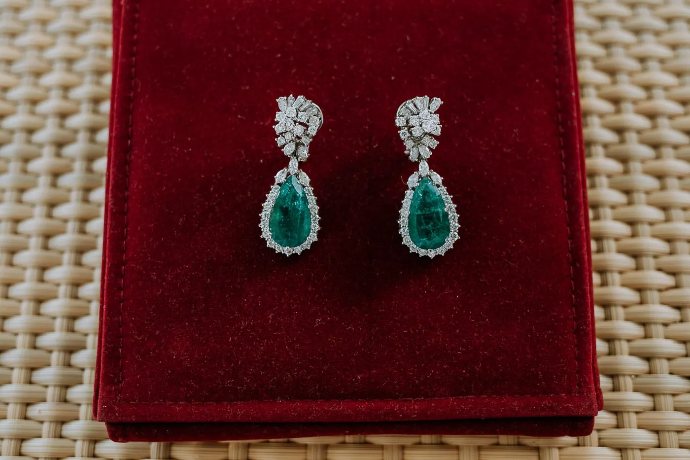 Emerald and diamond drop earrings on red velvet