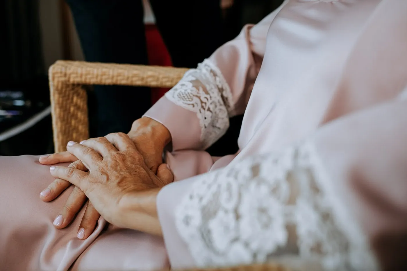 Bride's hands resting on her lap by the lace cuff of her robe