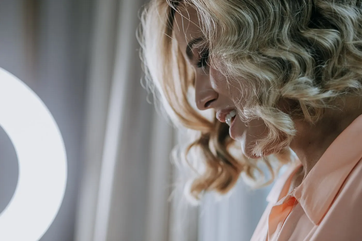 Guest with curled hair smiling in soft window light