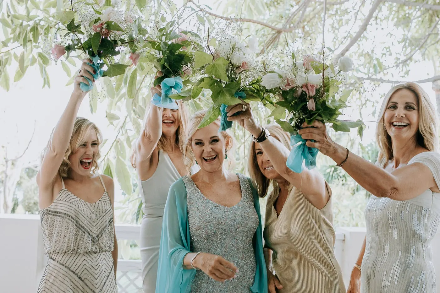 Friends raising their bouquets around the bride