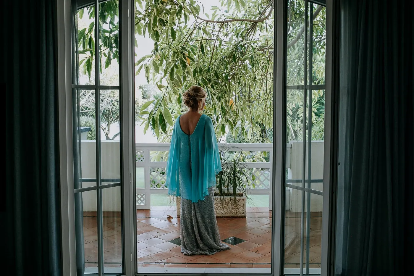 Bride in her turquoise cape stepping out onto the balcony
