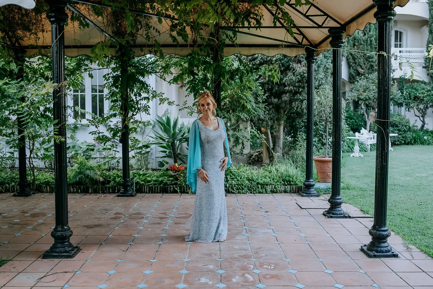 Bride under an iron pergola in the hotel gardens