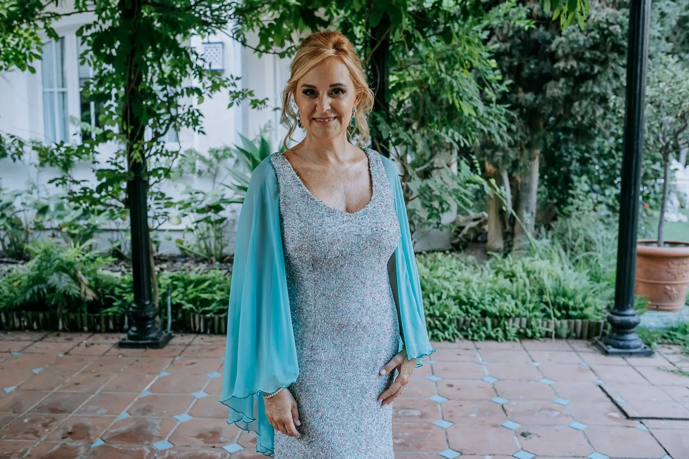Bride smiling under the pergola, her cape over her shoulders