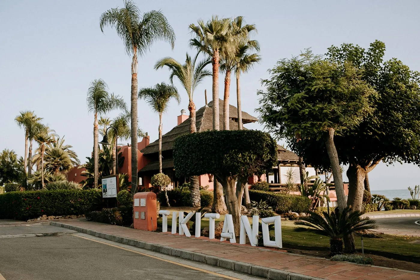 Tikitano sign by the road with the thatched roof and palm trees, Estepona