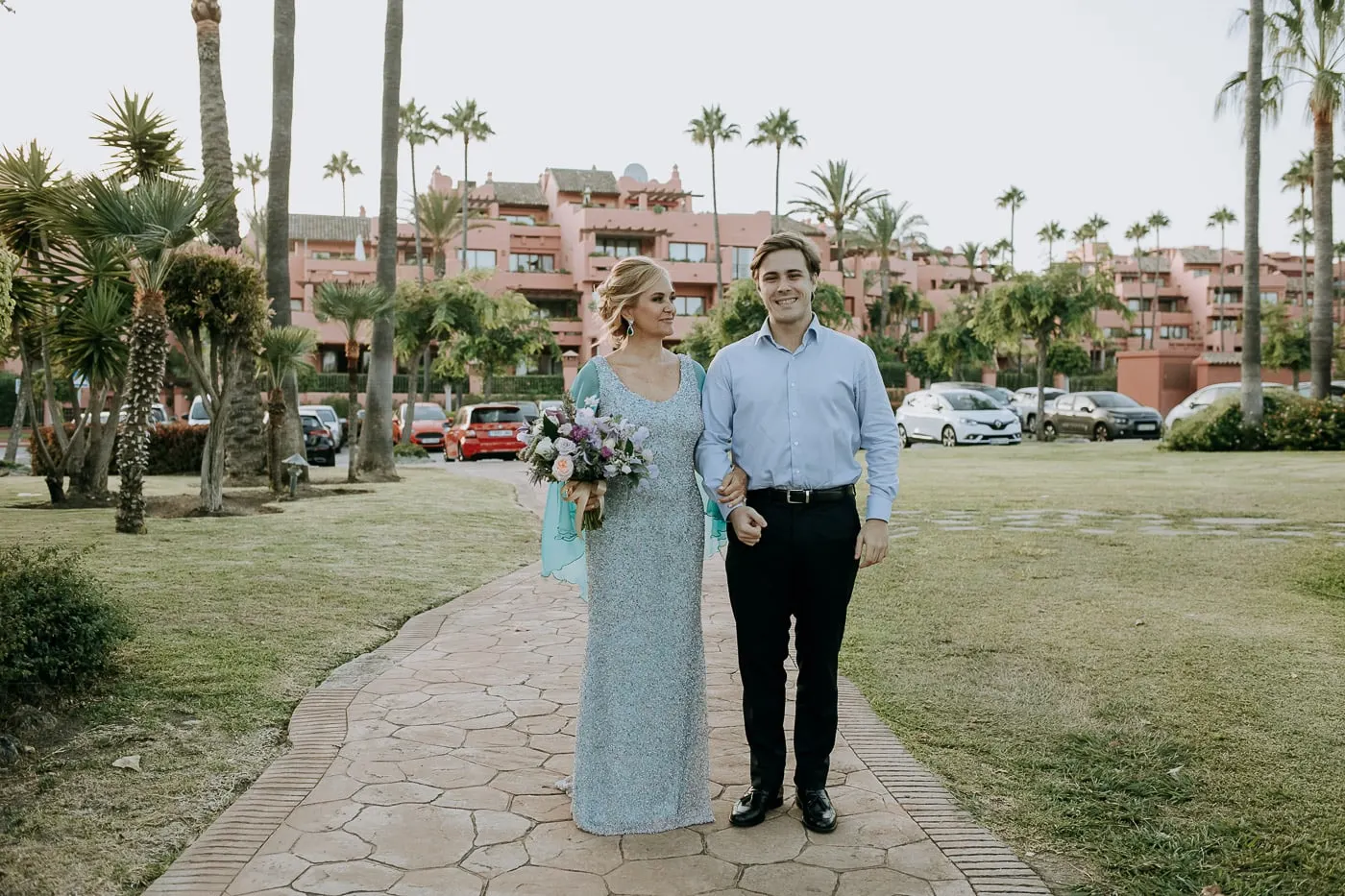 Bride arriving arm in arm with a young man in a blue shirt