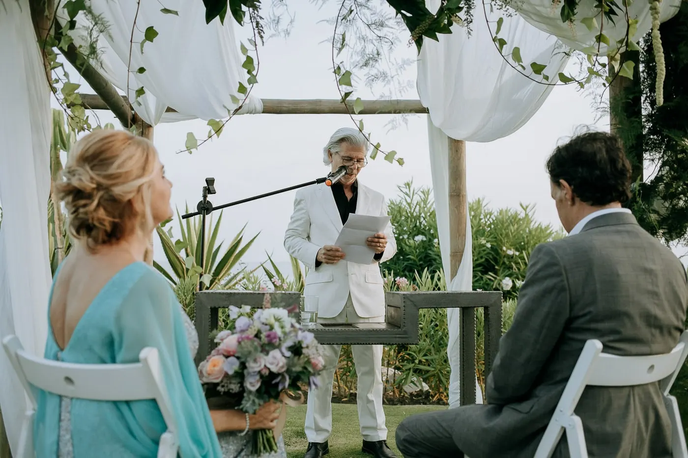 Officiant reading under the white drapes of the arch
