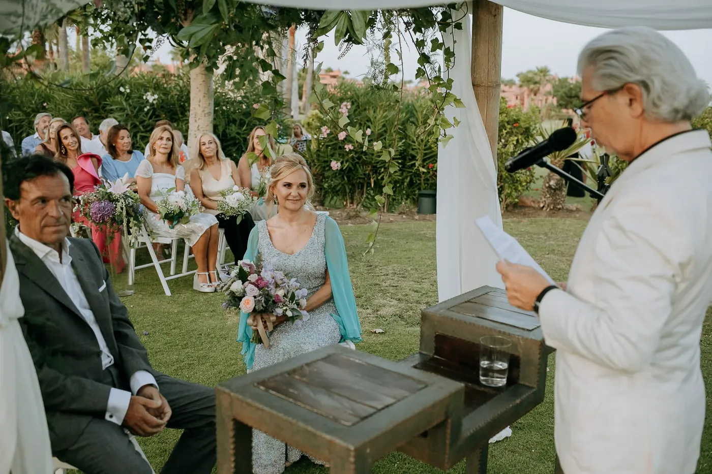 Officiant in white reading as the couple listen