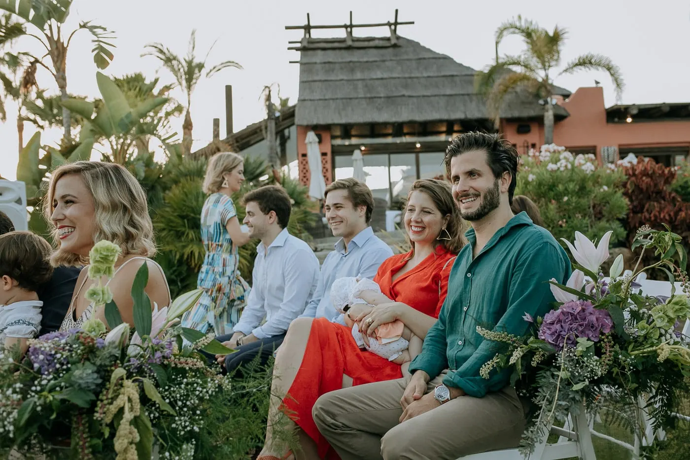 Guests seated in the garden with the thatched roof behind