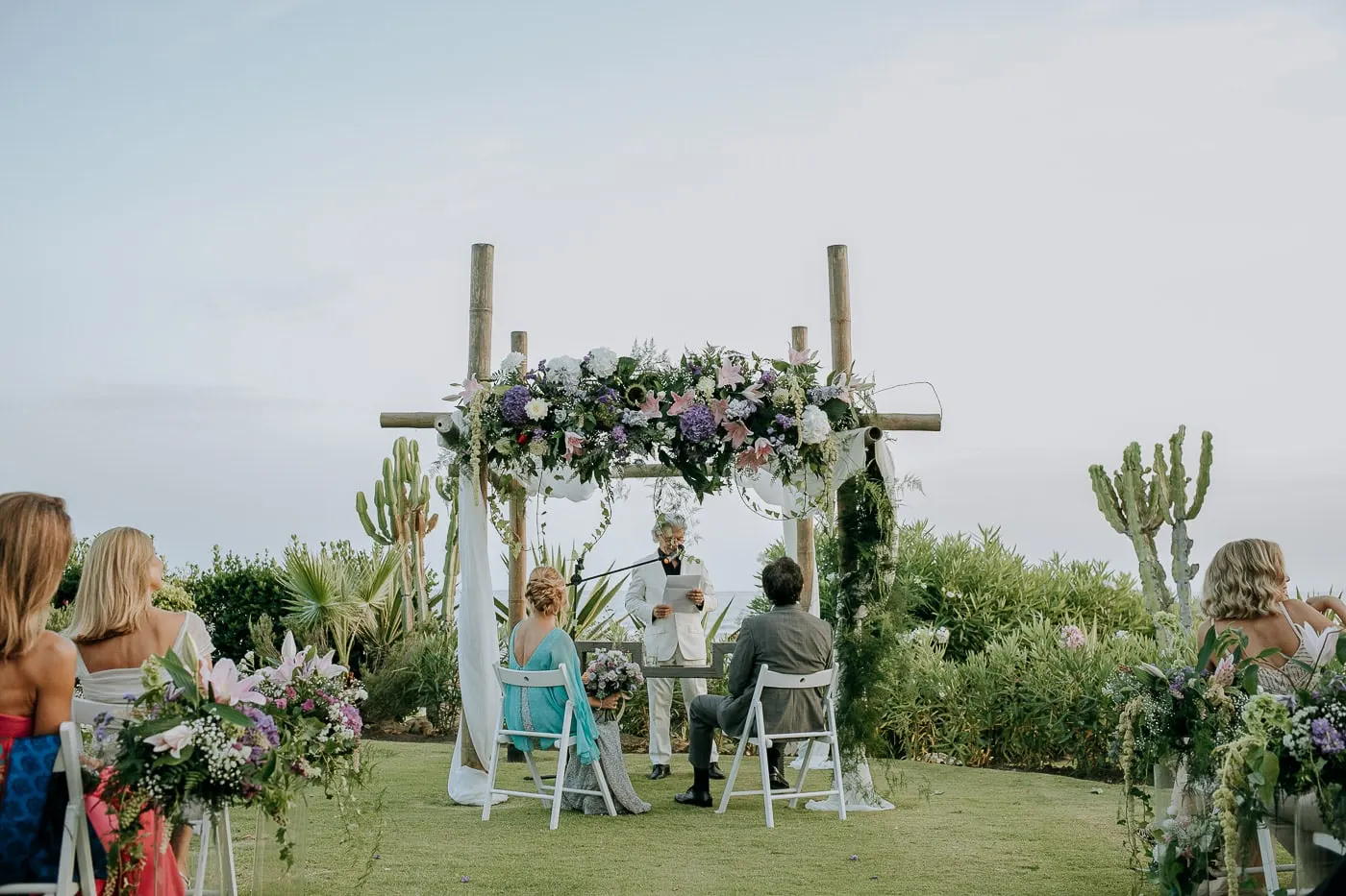 Flower arch of lilac, white and purple blooms in front of the sea, Tikitano