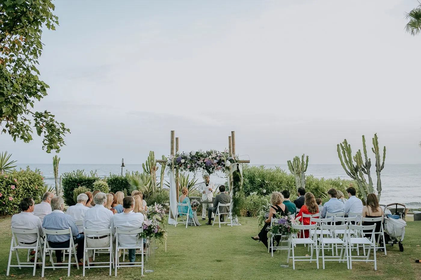 Garden ceremony from the back rows, sea and cacti behind the arch