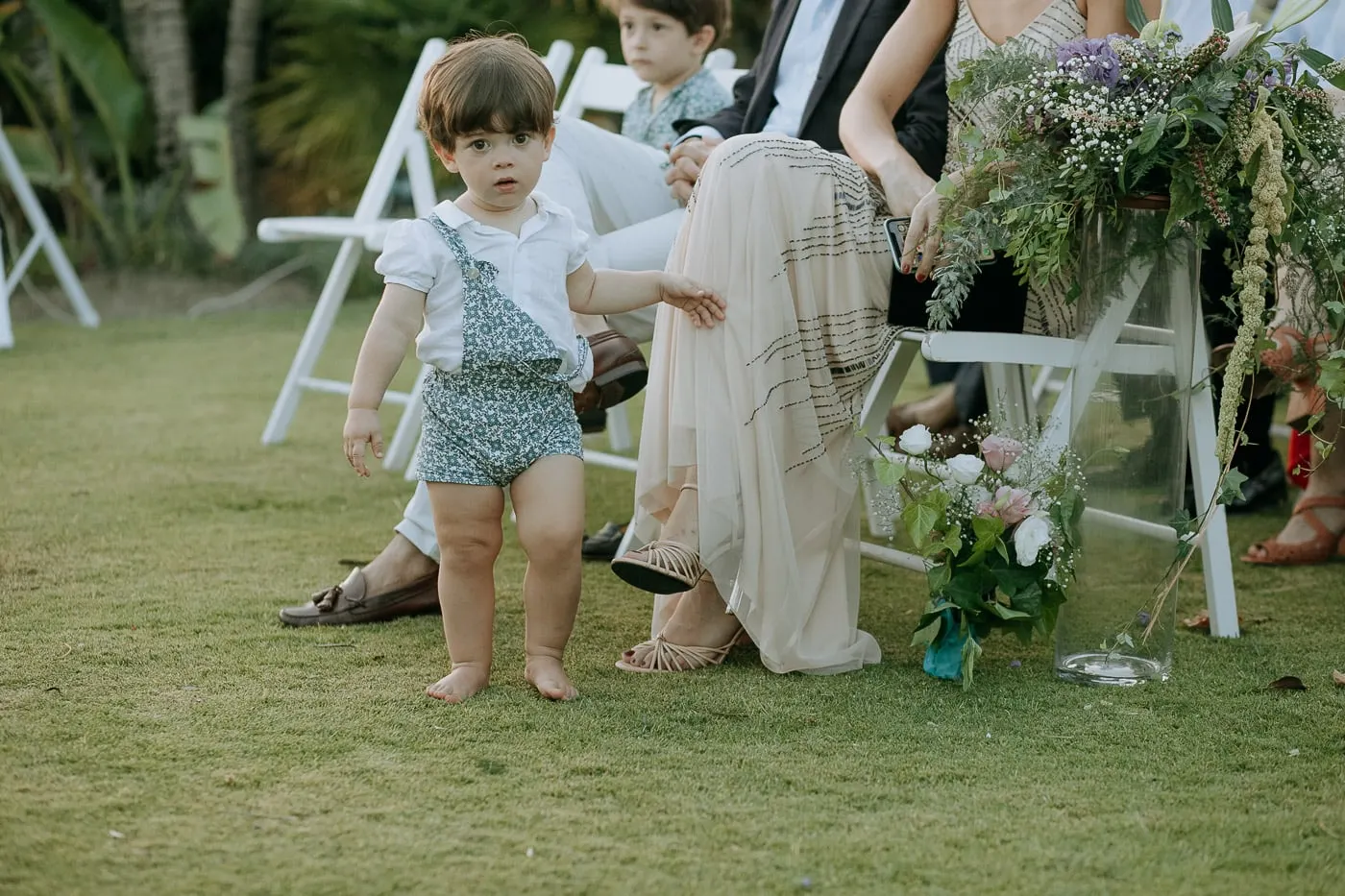 Toddler in blue dungarees wandering between the chairs