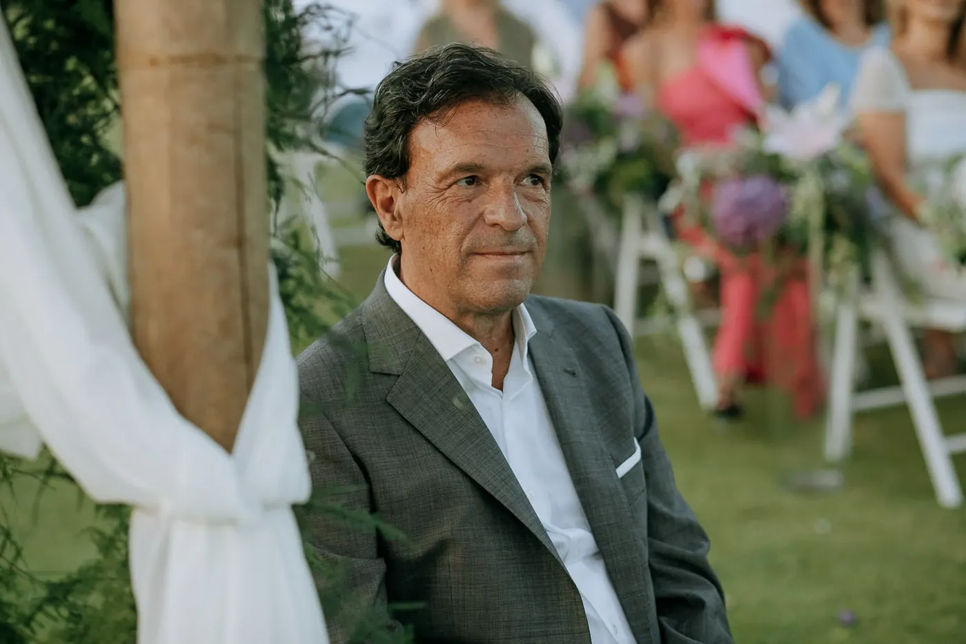 Groom listening to the ceremony, framed by white drapes