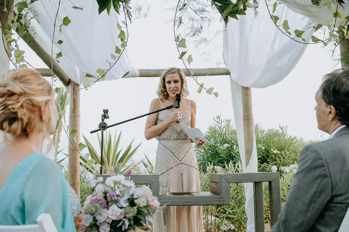 Friend in a beaded dress giving a reading at the microphone